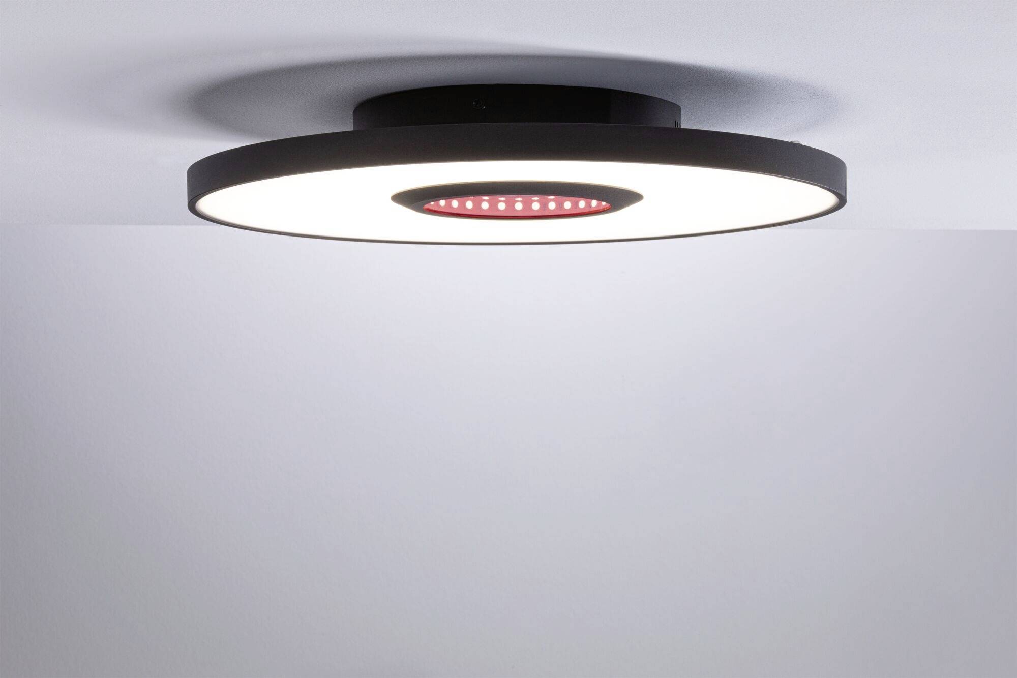 Rund loftslampe med sort kant og centralt rødt element, monteret på en hvid loft.