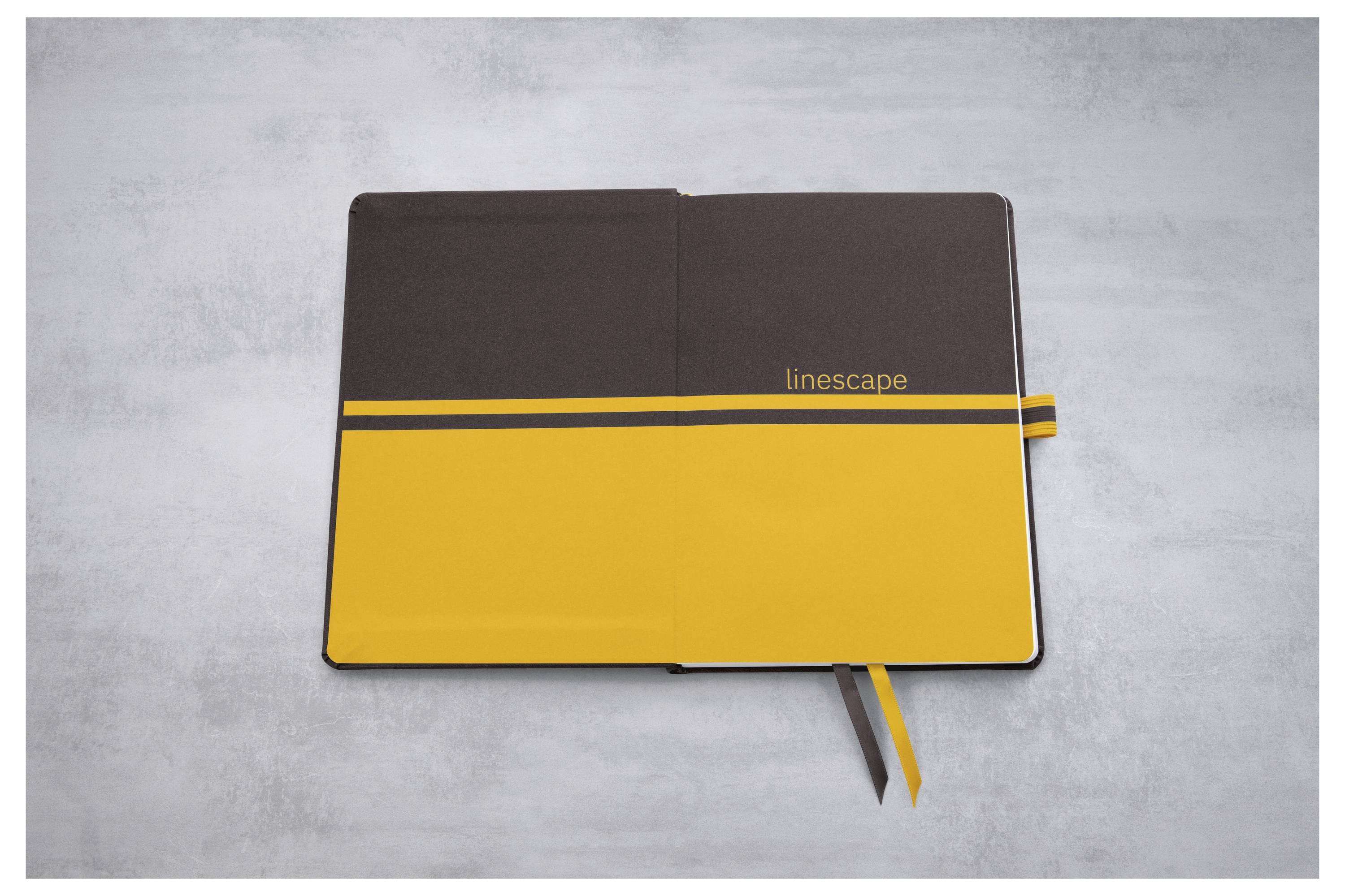 Lukket brun og gul notesbog med 'linescape'-mærkning, liggende på en grå overflade med synlige bånd bogmærker.
