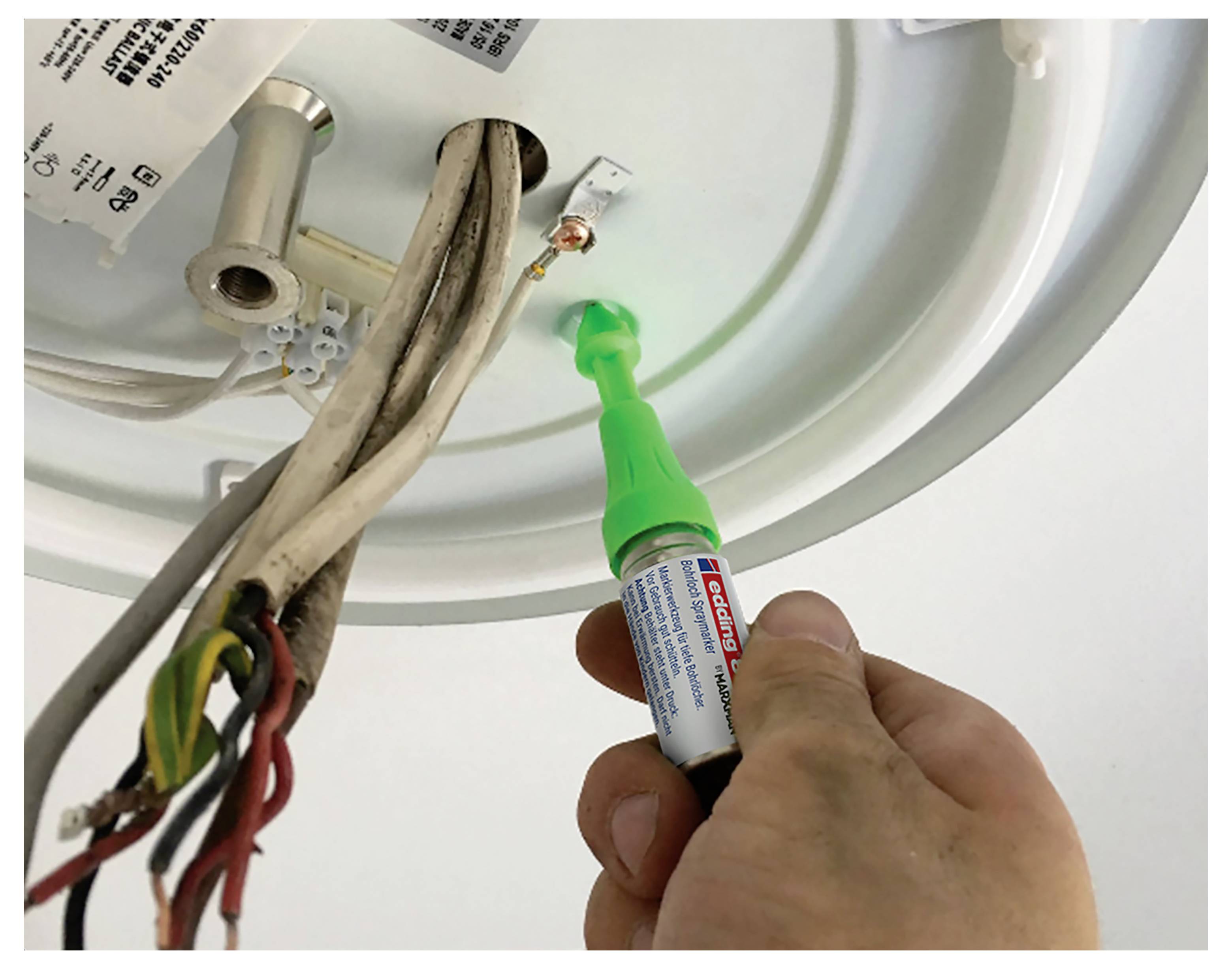 En person påfører lim på en loftlampefixtures trådforbindelse med hånden, mens vedkommende holder blottede elektriske kabler.