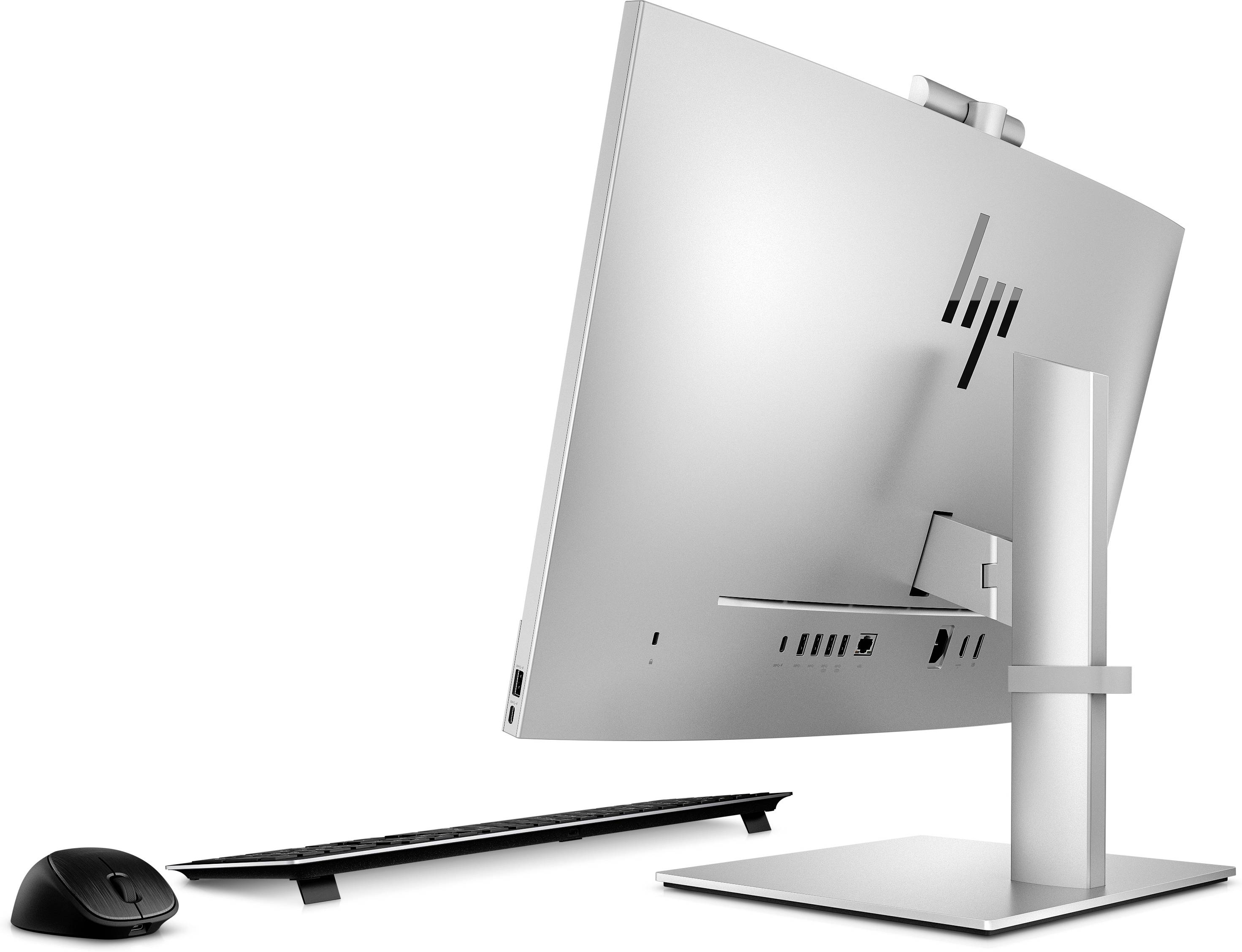 En moderne all-in-one-computer i sølvfarve med en tynd bagside, ledsaget af et trådløst tastatur og en trådløs mus.