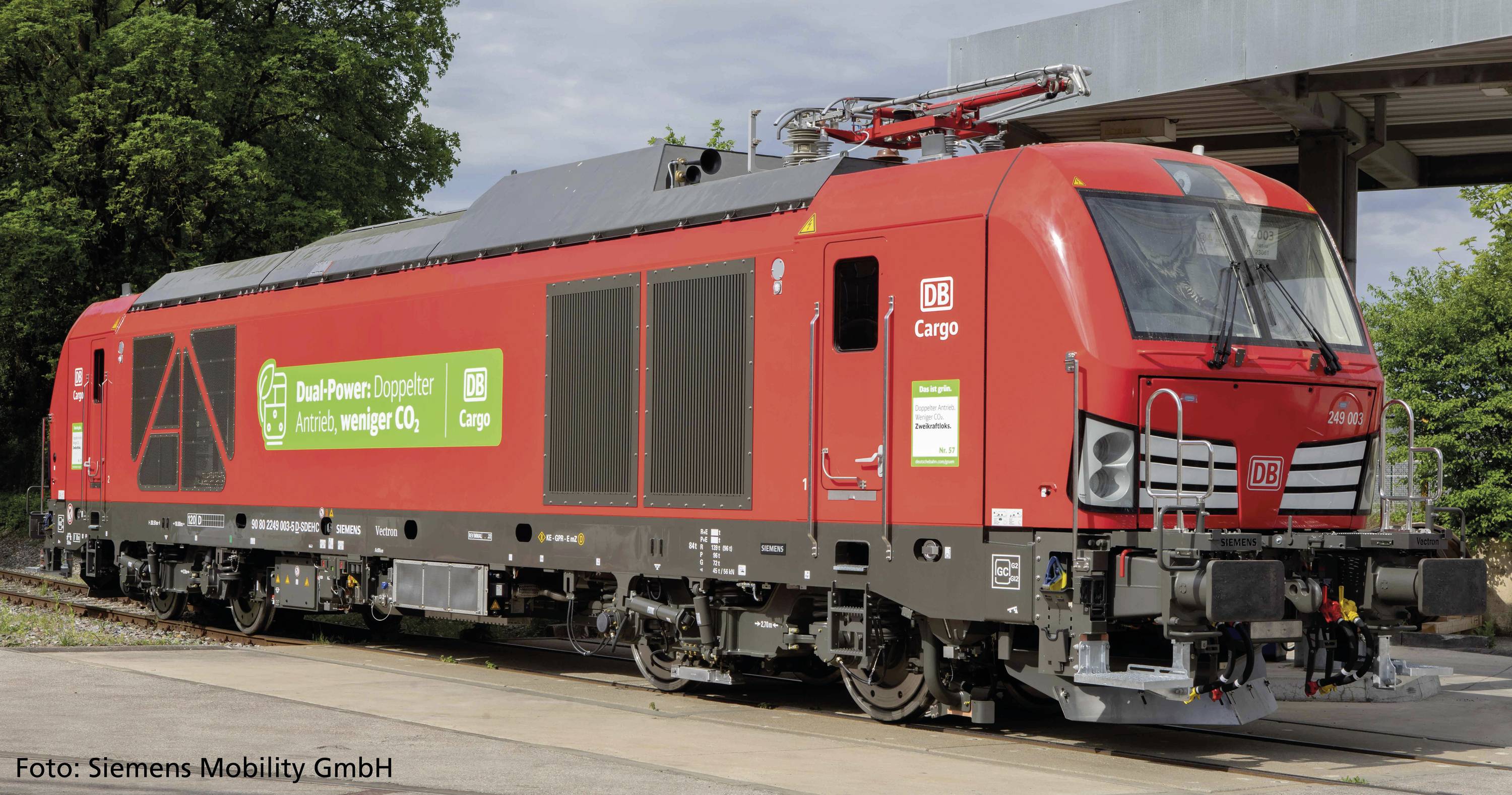 Et rødt godstog fra Deutsche Bahn med påskriften 'DB Cargo' holder på et spor. Teksten på siden nævner miljøvenlig transport.