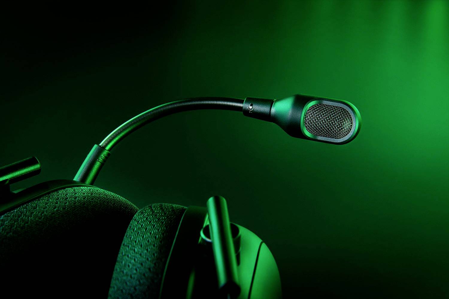 Et sort gaming-headset med aftagelig mikrofon foran en grøn, oplyst baggrund.