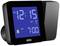 Digital vækkeur med blåt display viser '12:15'. Alarm indstillet til '7:00'. Mærket 'Braun' er synligt.