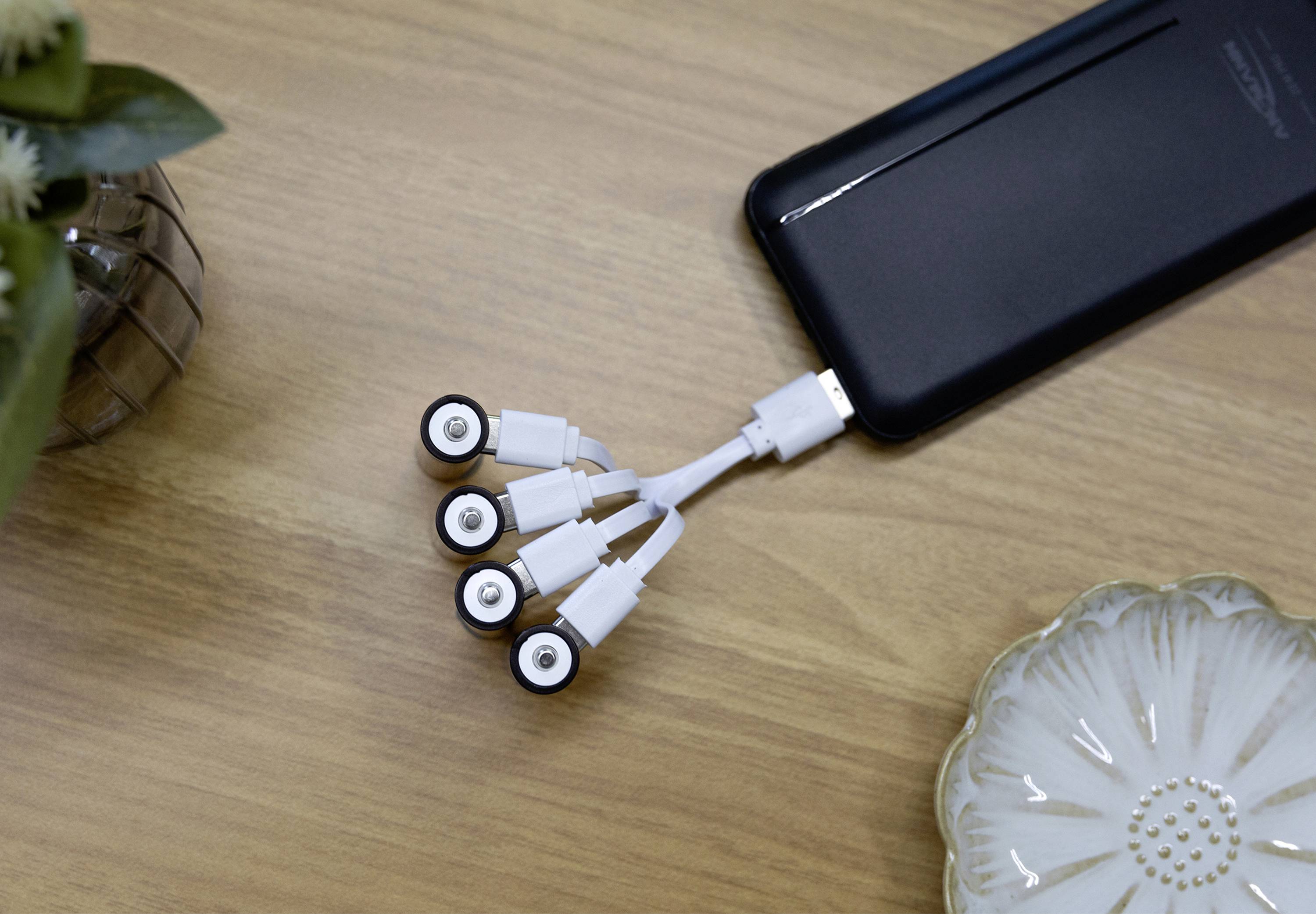 En enhed med et USB-kabel, der er splittet i fem dele, er placeret på et træbord.