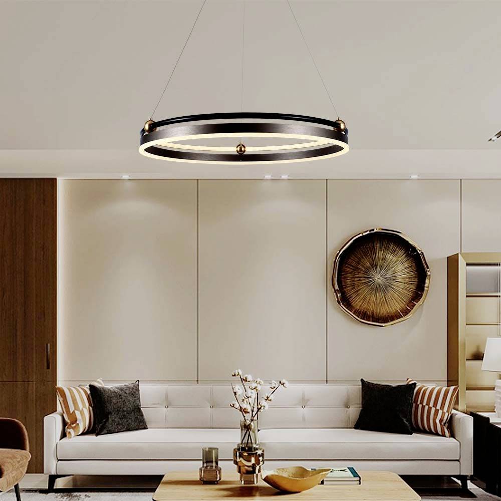 Et moderne stue med en hvid sofa, dekorative puder, en ophængt loftslampe og et rundt vægkunstværk.