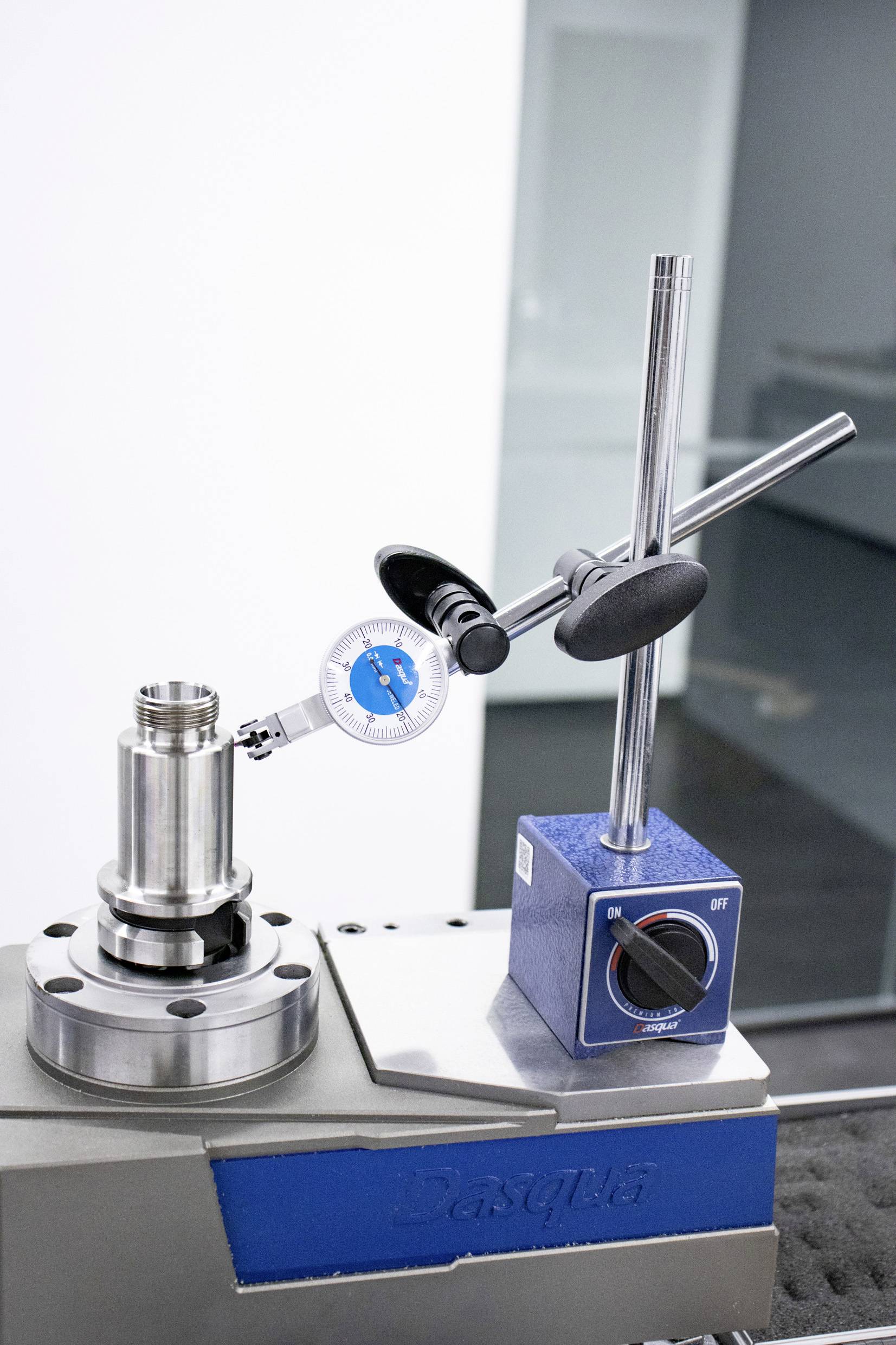 Et præcisionsmåleinstrument måler diameteren på en cylindrisk metalgenstand. Det står på et laboratoriebord i et teknisk laboratorium.