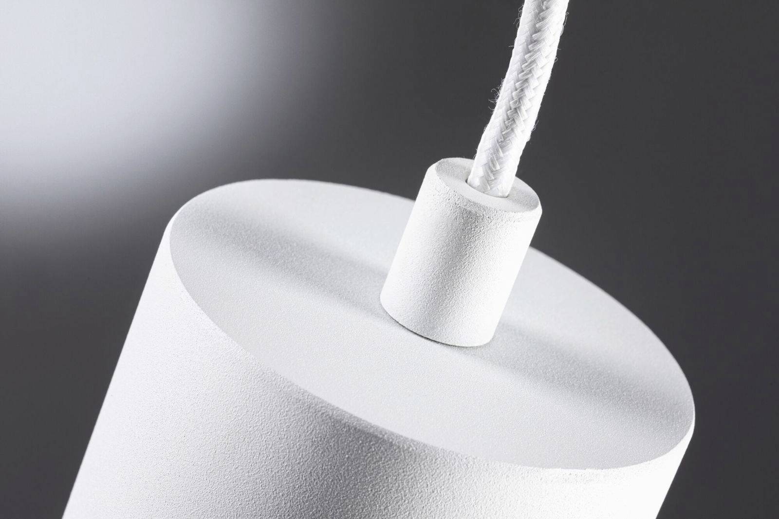 Hvid cylinderformet lampe hænger fra loftet. En klar baggrund fremhæver det minimalistiske design.