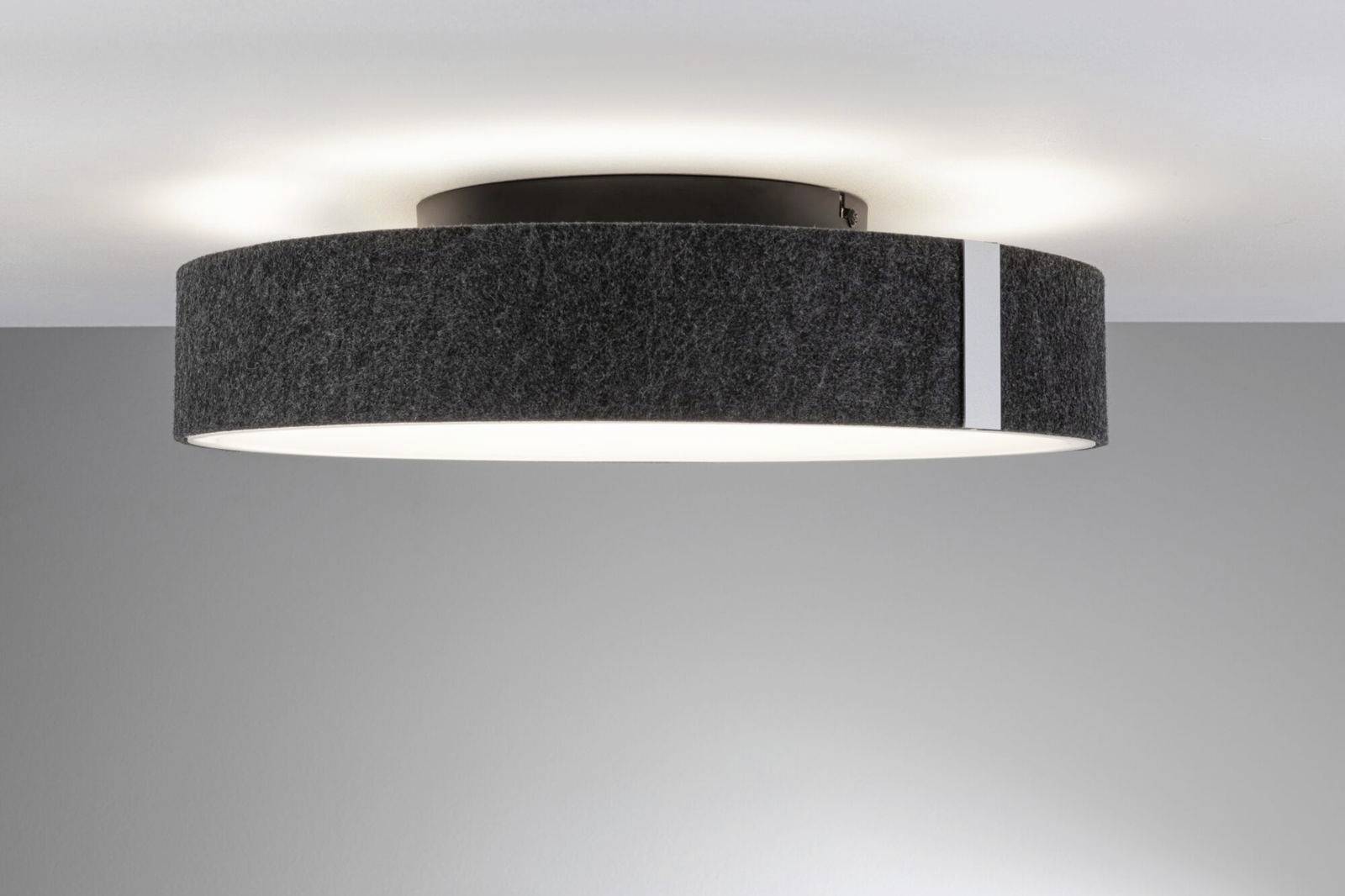 En rund, sort loftslampe med hvid stribe, som spreder diffust lys i et moderne rum.