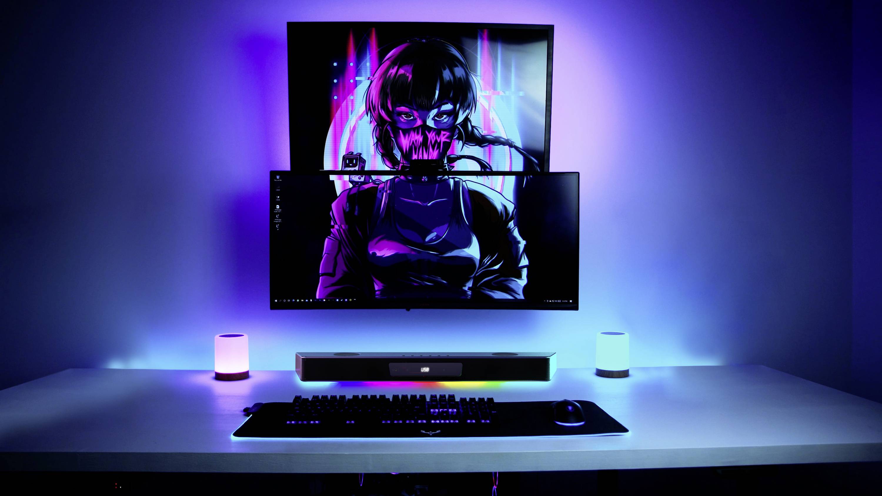 En moderne computerarbejdsplads med to monitorskærme. Skærmene viser et cyberpunk-design. Omgivelserne er belyst i blåt.