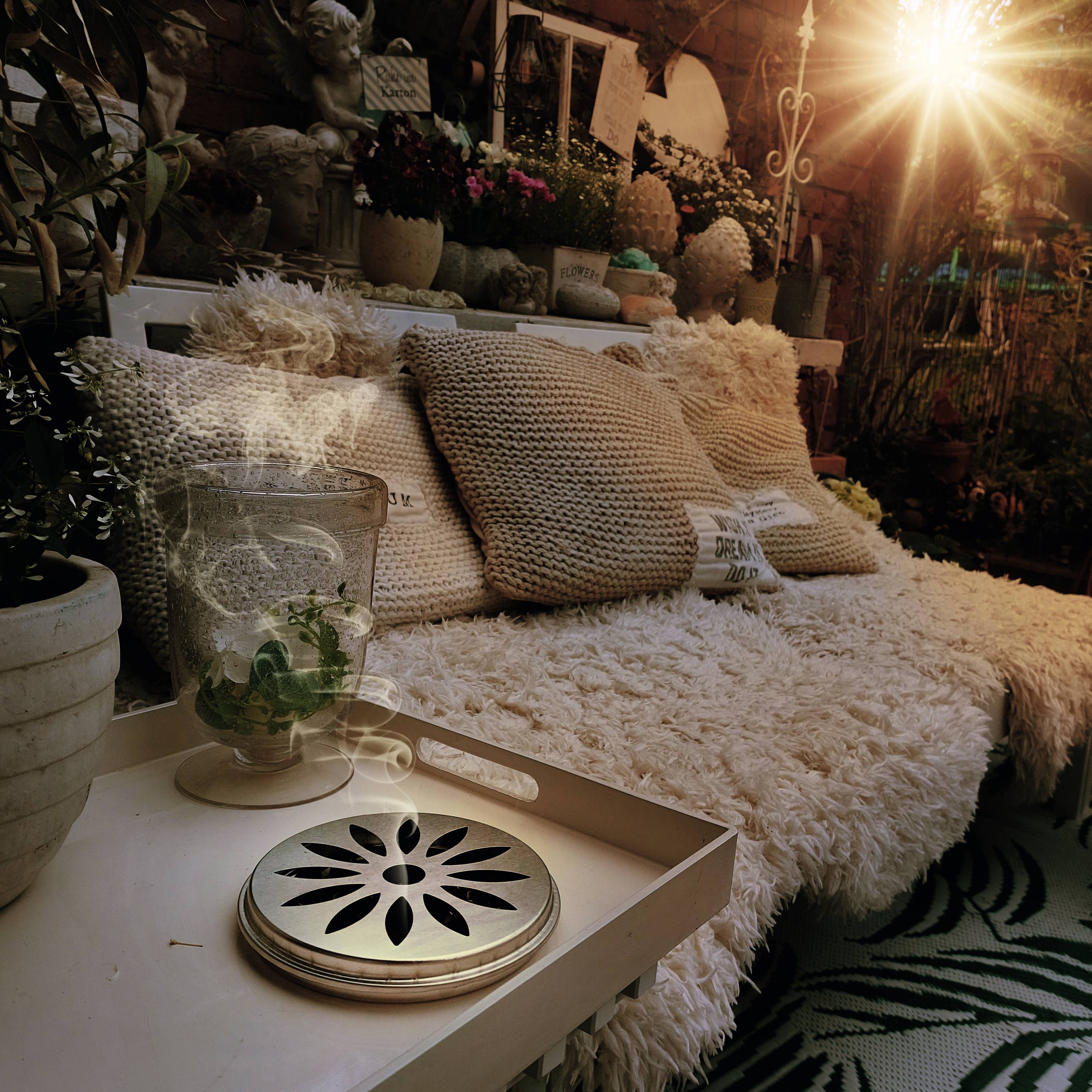 Hyggelig sidekrog med bløde, bløde puder og planter. Sollyset stråler oppefra og skaber en varm atmosfære.