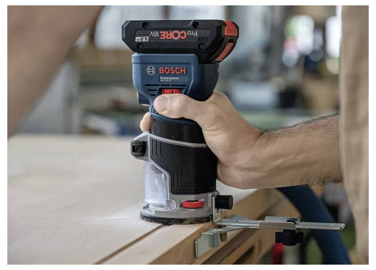 En person betjener en trådløs Bosch-router på en træoverflade og fokuserer på præcis træbearbejdning med en fastspændt kant som vejledning.