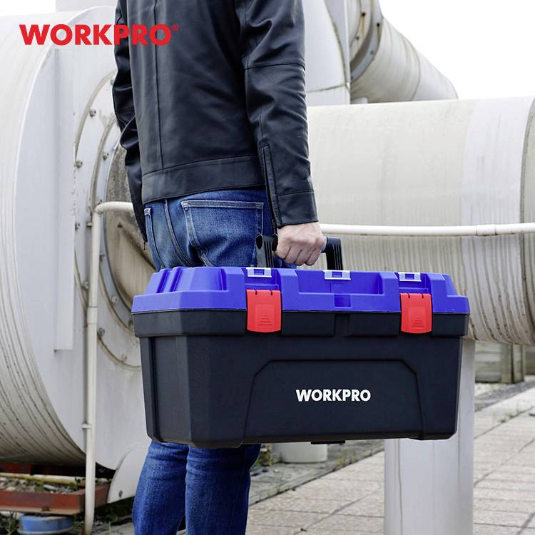 'Person med mørkblå værktøjskasse fra WORKPRO går forbi store rør. Kassen har røde låse og blå afdækning.'