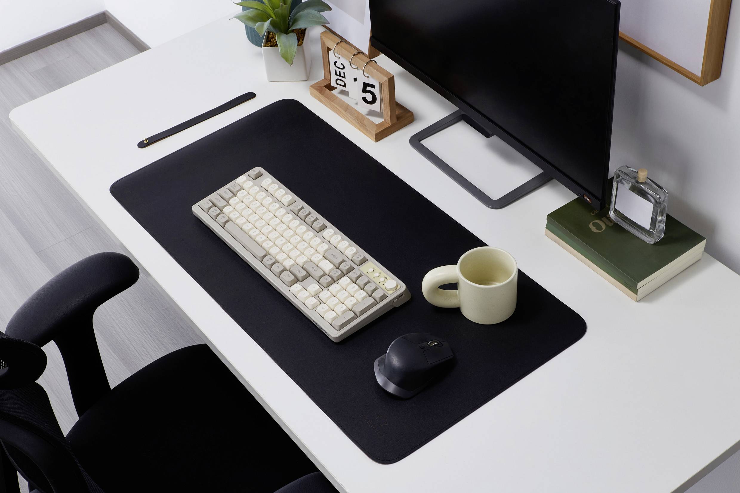 Et ryddeligt skrivebord med computer, tastatur, mus, kop og dekorationer. Dato på kalenderen: 5. december.