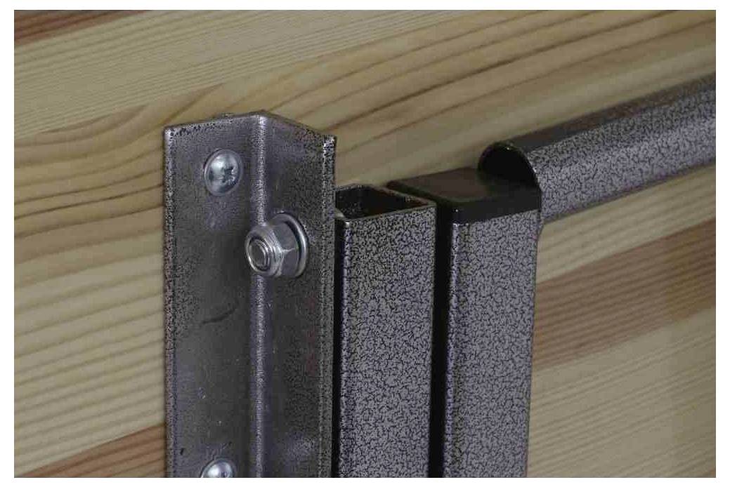 Nærbillede af et robust metalhængsel, der forbinder to træelementer. Hængslet er fastgjort med skruer og har en blank overflade.