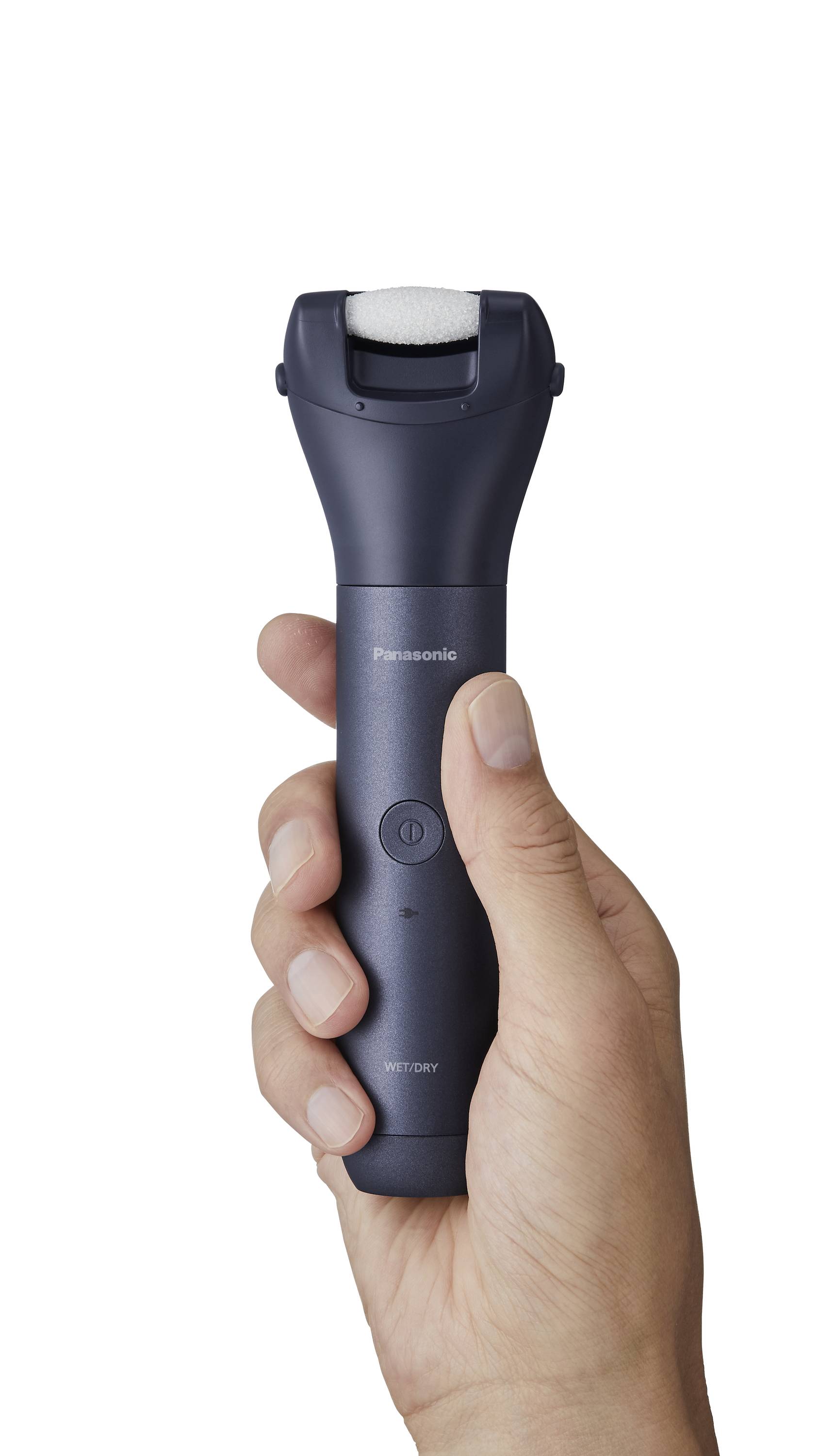 En hånd holder en mørkeblå elektrisk fodplejeenhed med påsat rulle, klar til brug.