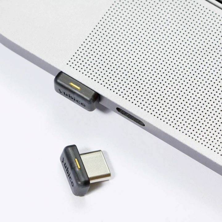 En USB-sikkerhedsnøgle er sat i en bærbar computer, en anden nøgle ligger ved siden af. Begge er fra Yubico.