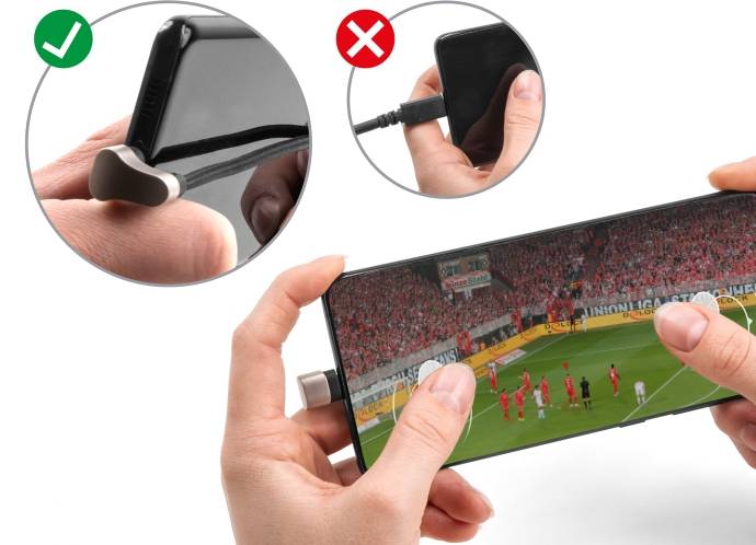 To hænder holder en smartphone med en fodboldkamp. Øverst til venstre: 'Rigtigt' viser smartphone i siden, øverst til højre: 'Forkert' med kabel.