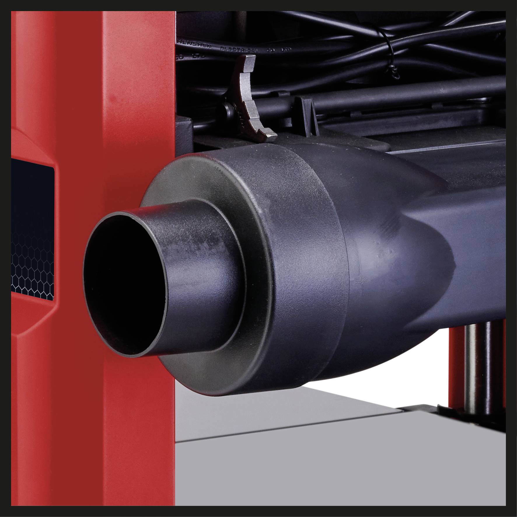 Et stort sort udstødningsrør med en rød metalramme i baggrunden, muligvis en del af en maskine eller et køretøj.