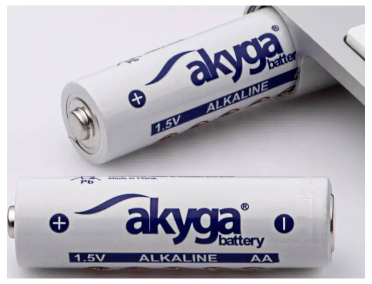 To AA-alkaline-batterier af mærket 'akyga' i forgrunden. Et batteri ligger fladt, det andet står let på skrå.