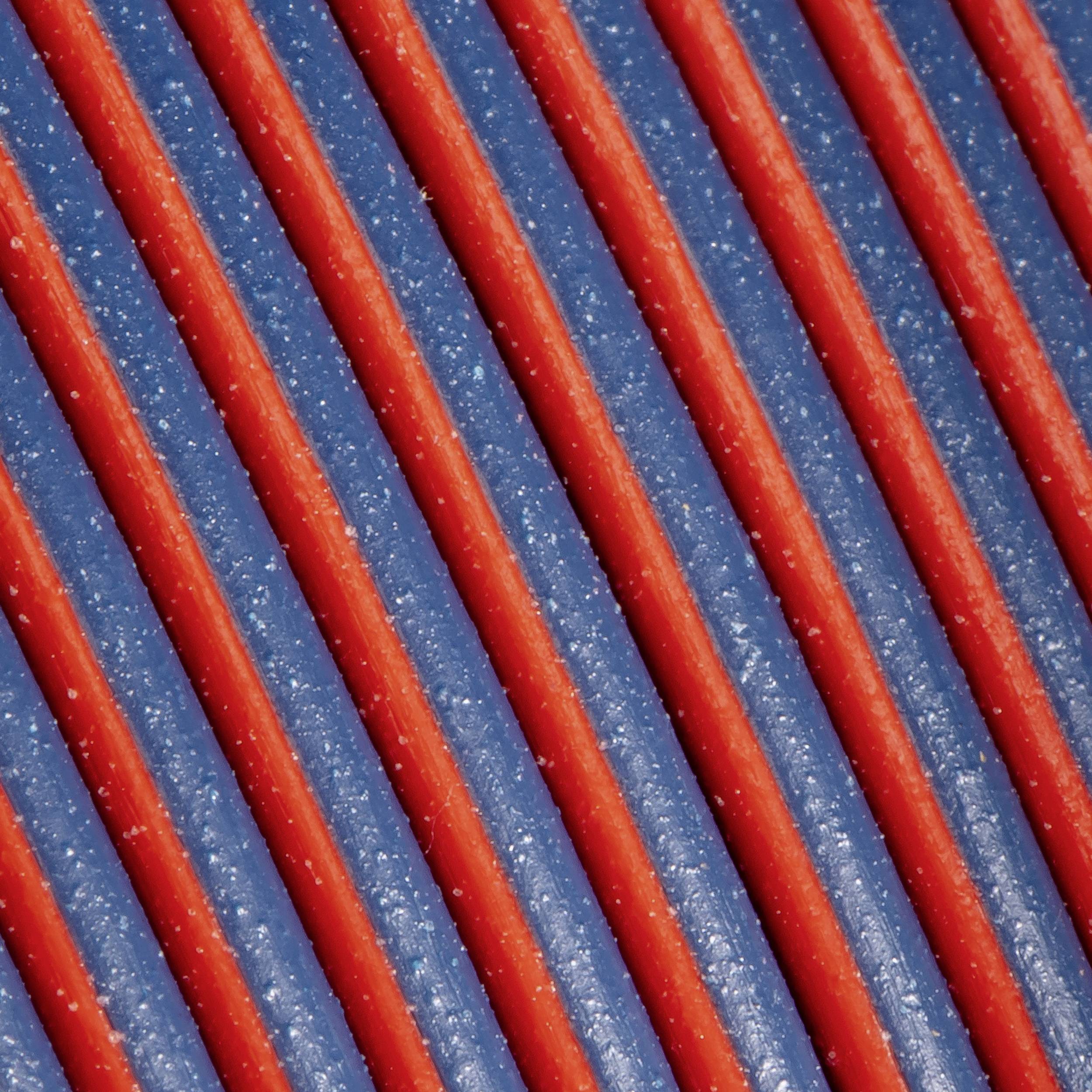 Nærbillede af røde og blå stribede baner, der løber diagonalt. Teksturen virker kornet og reflekterer lys.