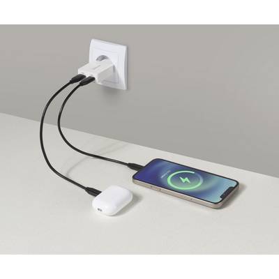 En telefon og trådløse ørepropper, der oplades på en disk ved brug af en dobbelt USB-netadapter; telefonskærmen viser et opladningssymbol.