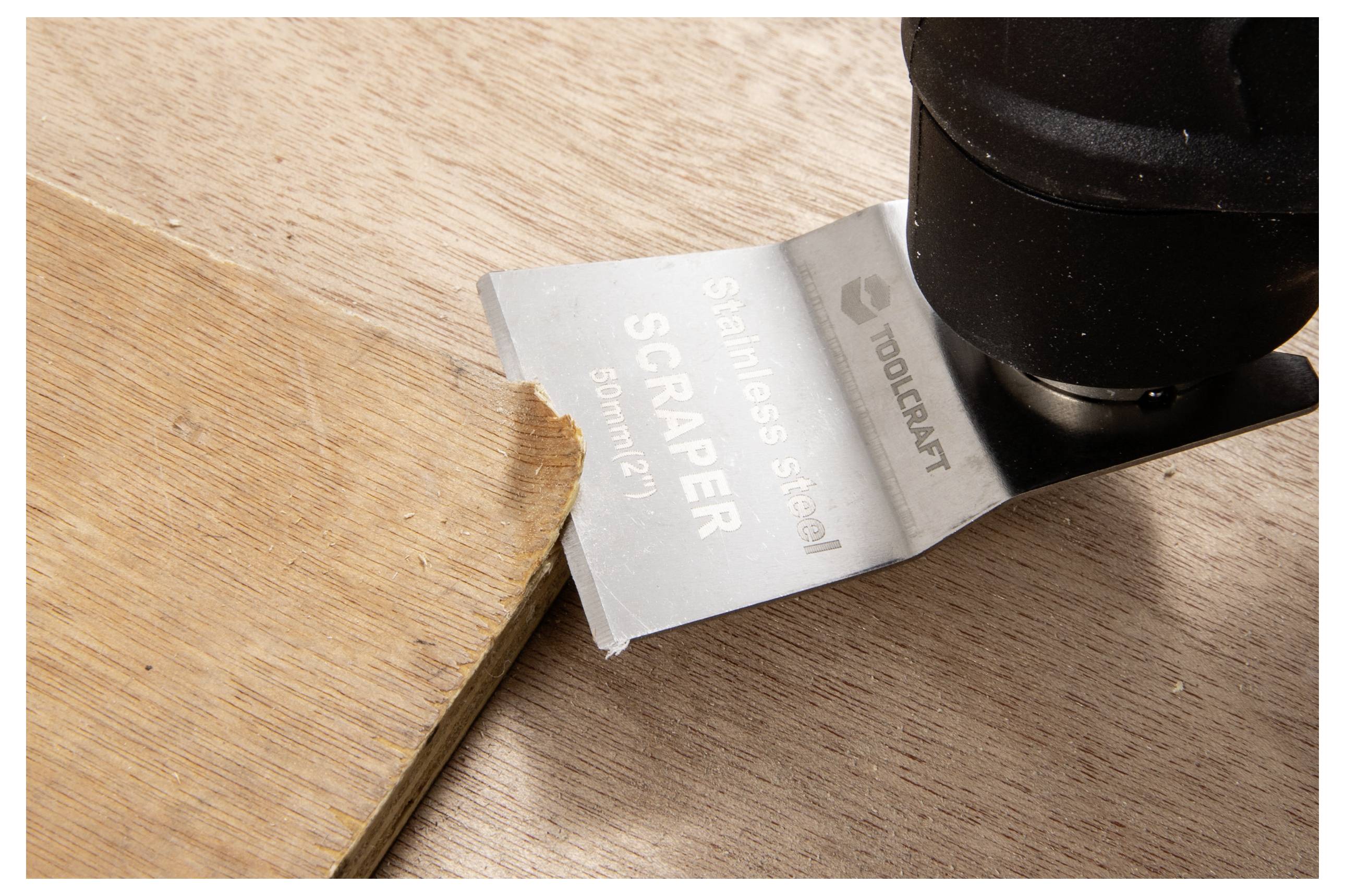 Et nærbillede af et skraberedskab, der fjerner en trækantet, med en metalklinge mærket 'Rustfri stål-skraber' med tydelig tekst.