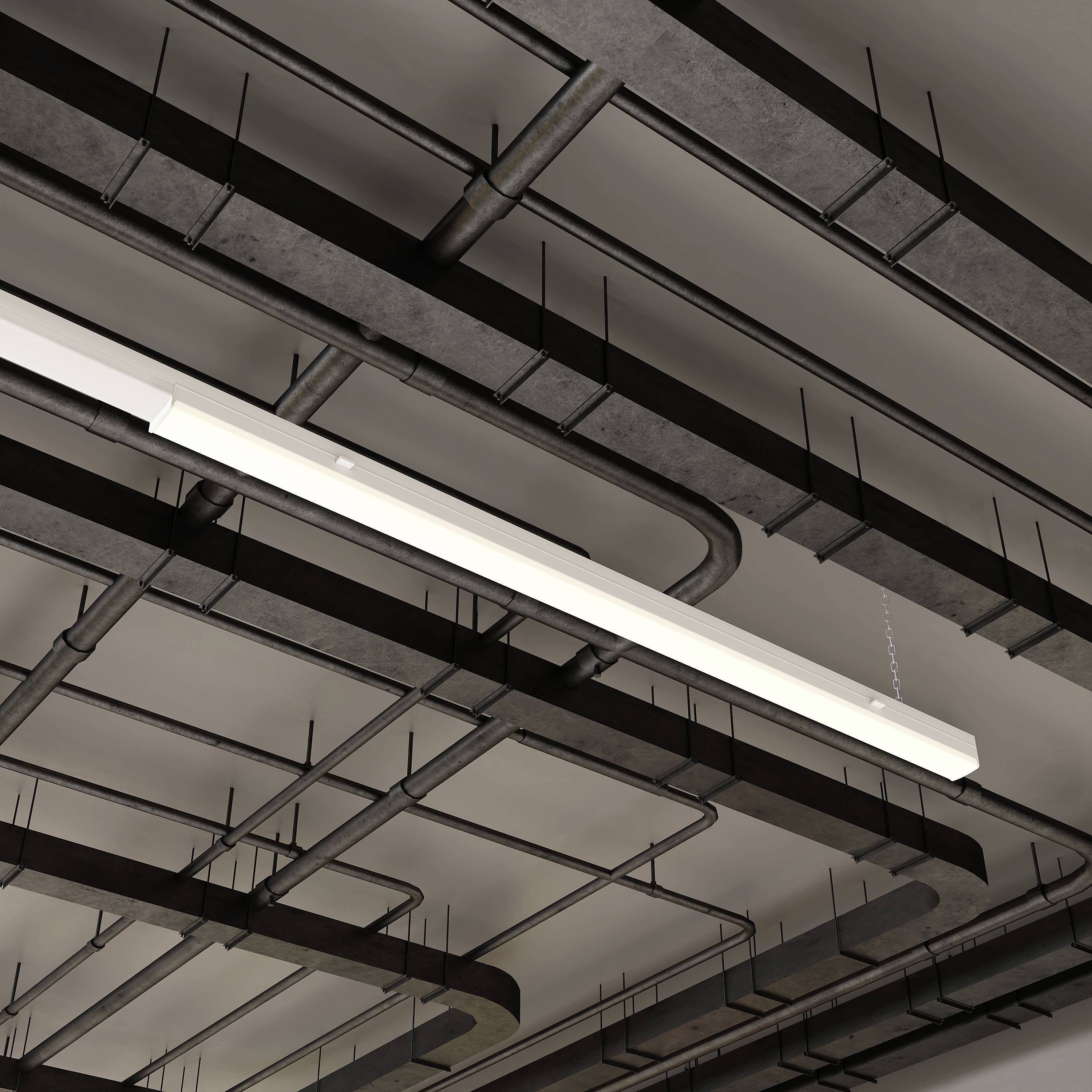 Industriel bygningsbjælke med synlige rør og en lang, rektangulær loftlampe. Minimalistisk og moderne design.