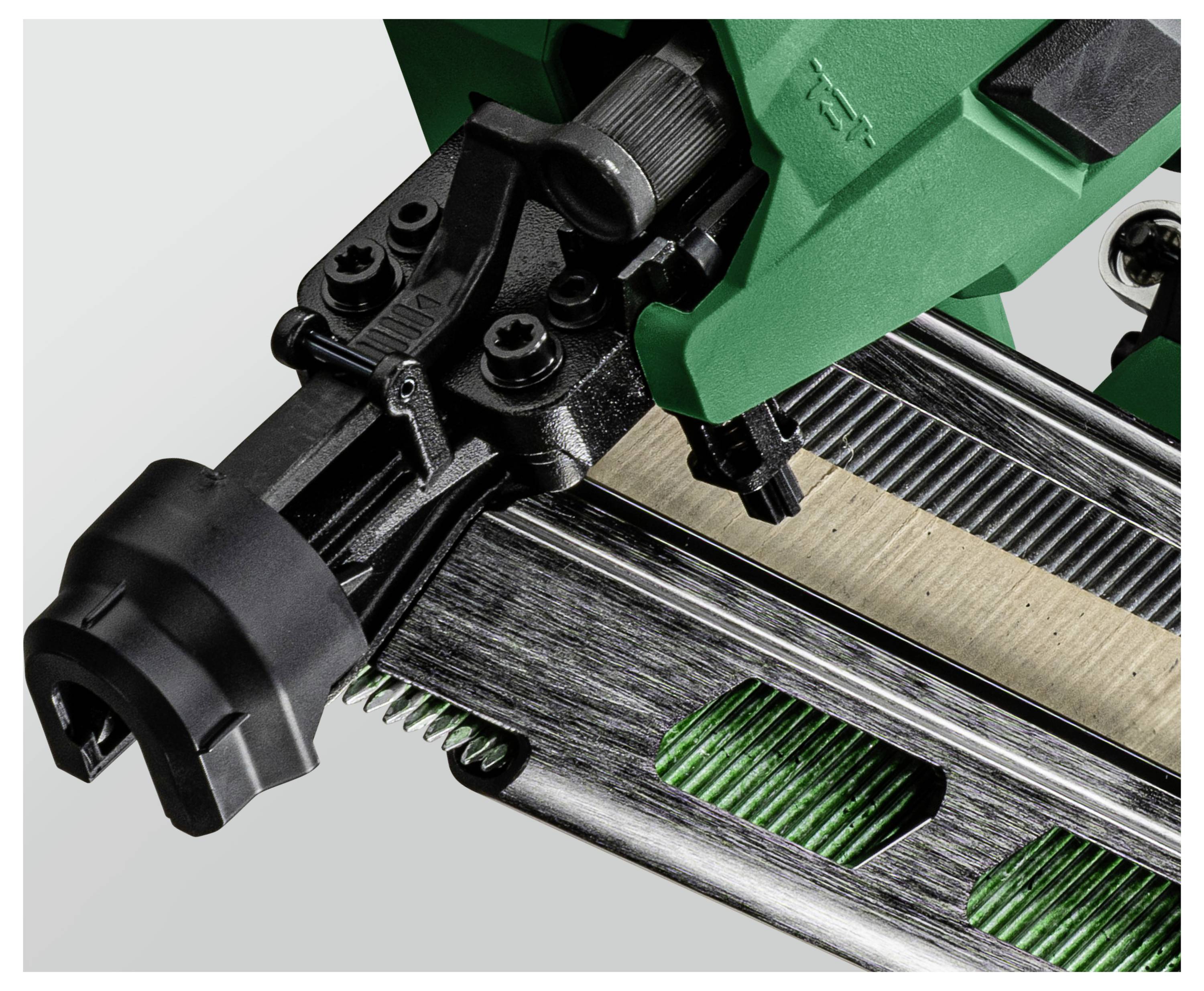 Et nærbillede af en grøn og sort hæftemaskine, fokuseret på hæftemekanismen og metalstrimler til hæfteklammer, der indfanger dens detaljerede konstruktion.