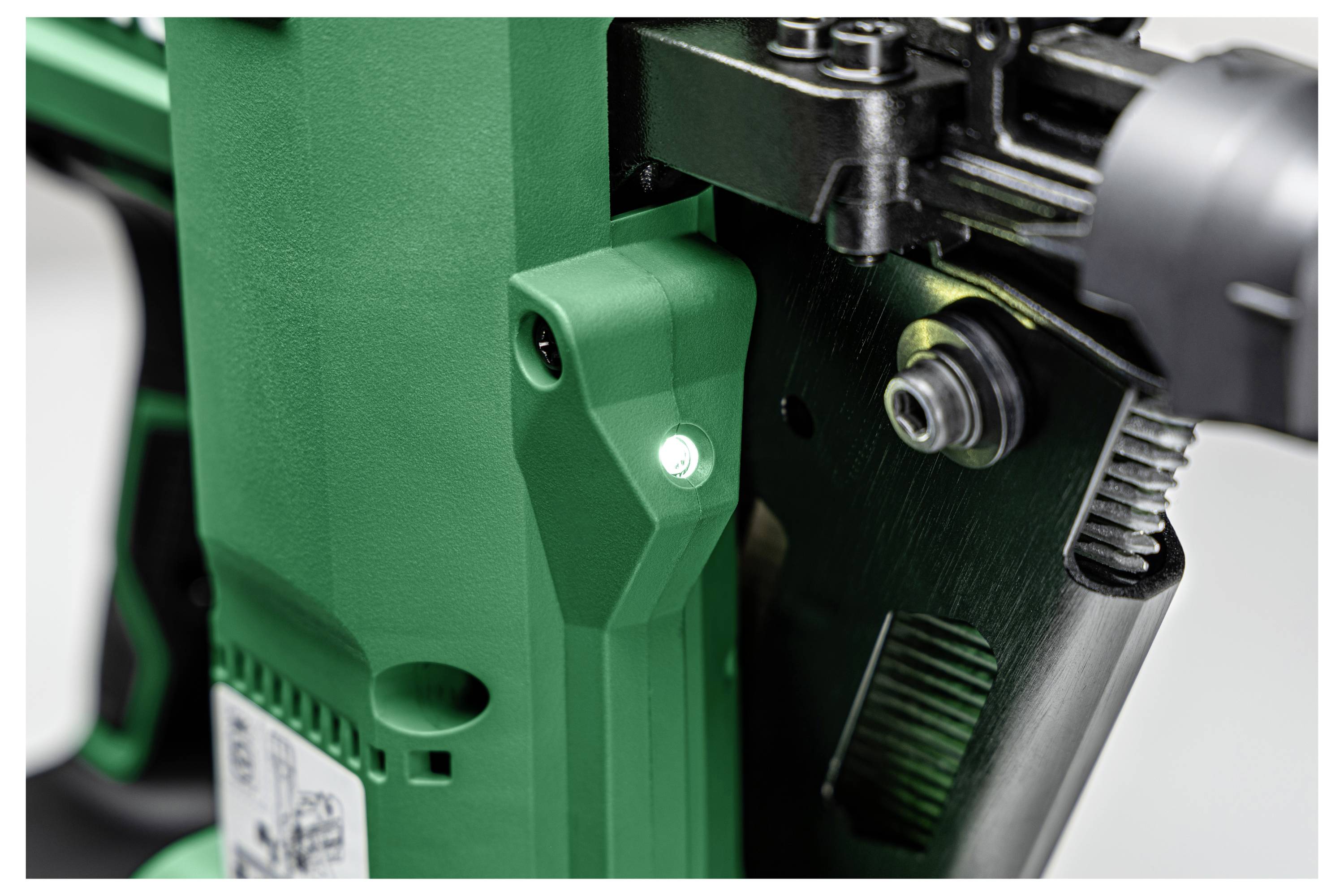 Nærbillede af et grønt og sort industrielt værktøj, med en skrue og en lille LED-lampe.