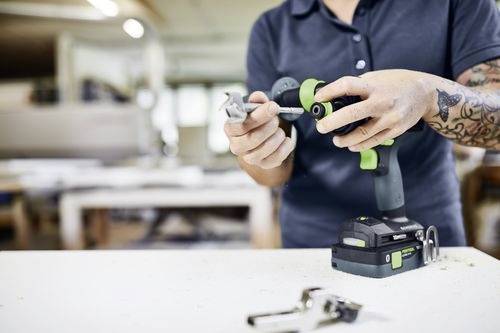En person bruger en trådløs boremaskine til at montere et beslag i et værksted og demonstrerer derved en bygnings- eller gør-det-selv-opgave.