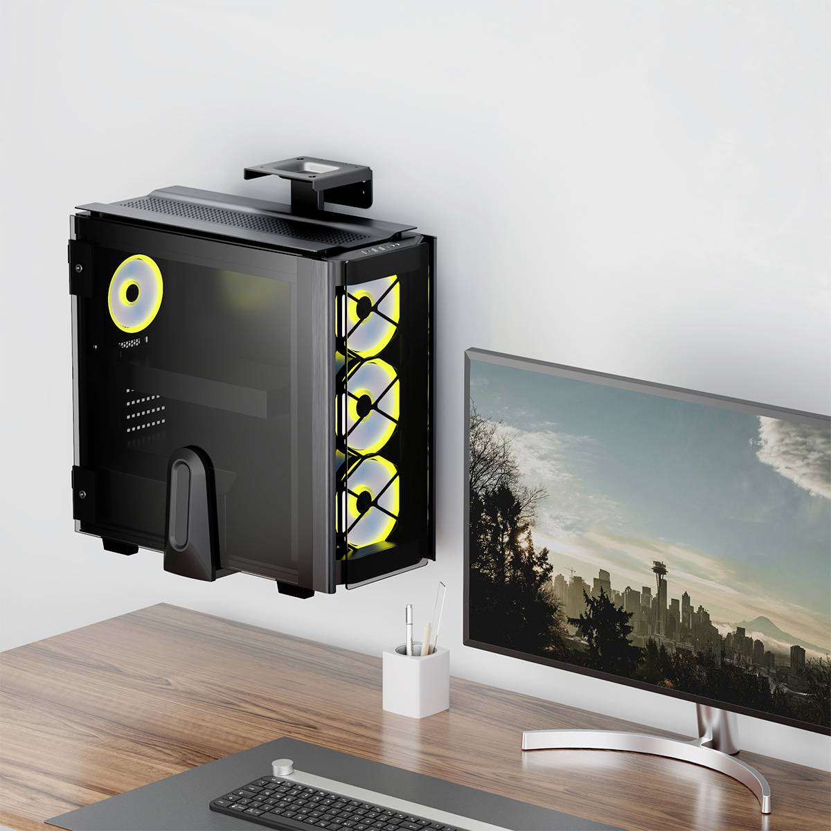 Et moderne skrivebordssæt med en vægmonteret PC med synlige køleblæsere, placeret ved siden af en widescreen-skærm, der viser en skyet himmel.