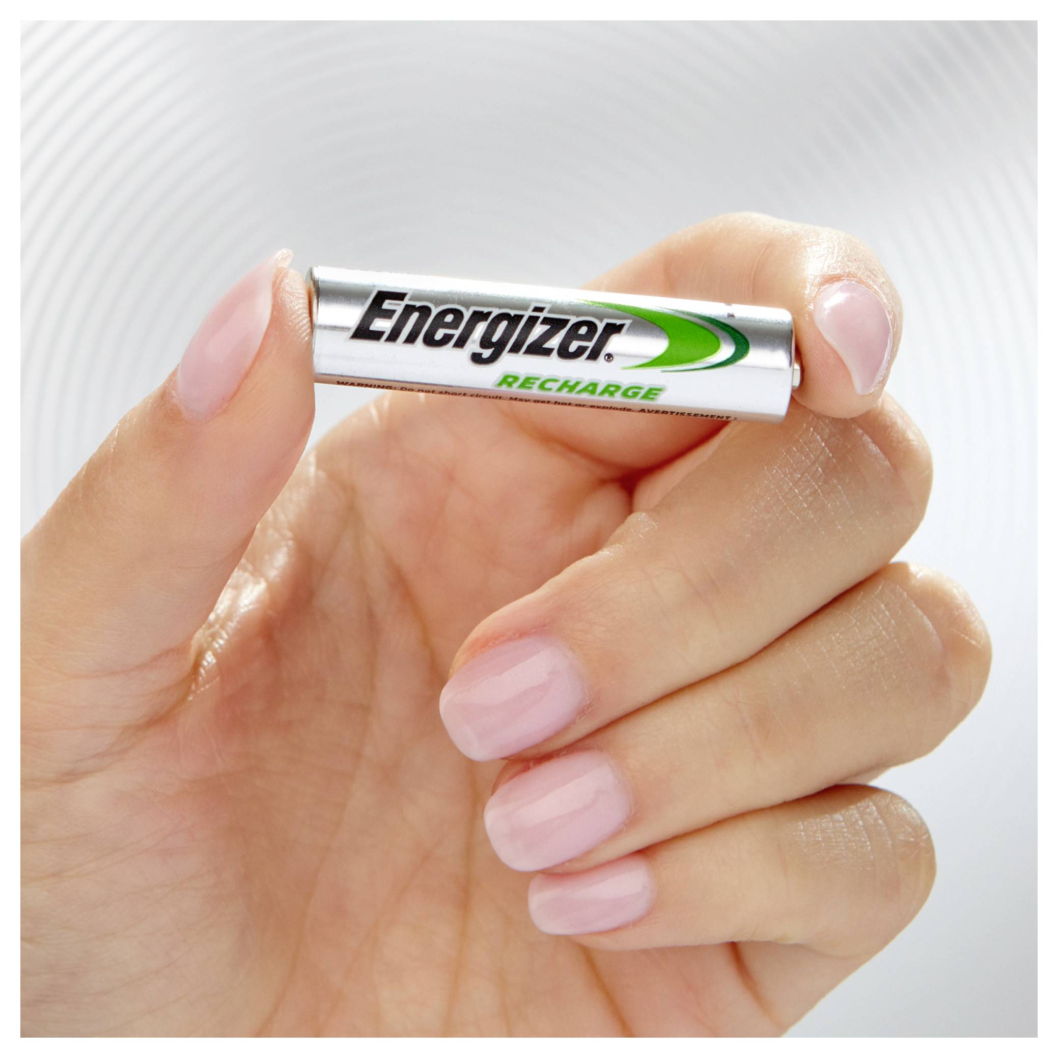 En hånd holder et sølvfarvet Energizer-batteri med grøn skrift 'Recharge', fokus er på batteriet.