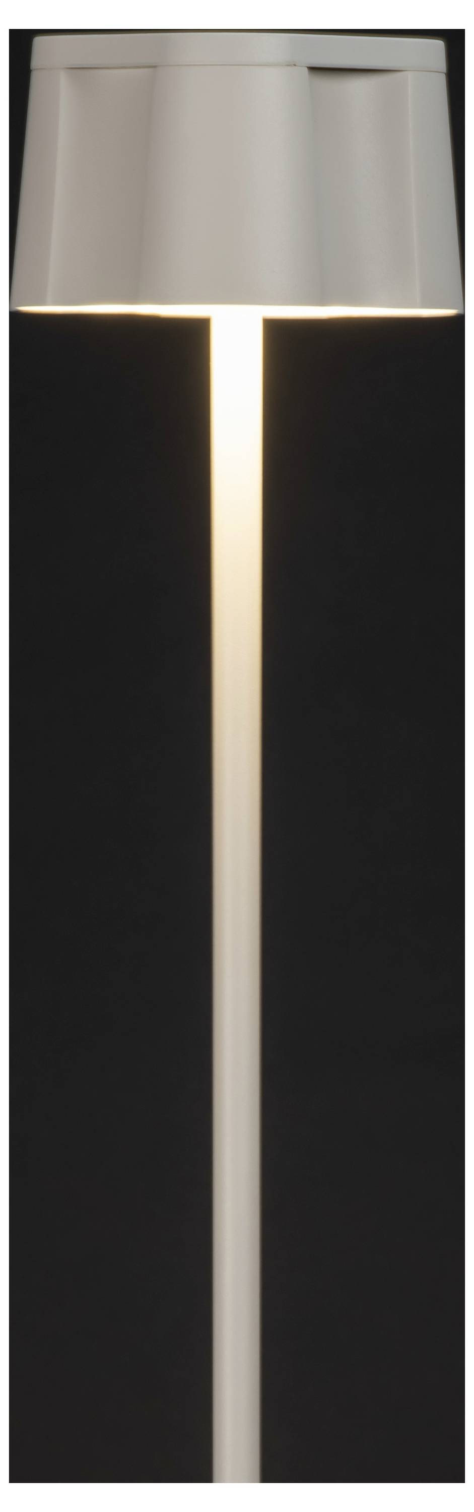 En elegant, moderne bordlampe med en cylinderformet skærm udsender et varmt, blødt lys mod en mørk baggrund.