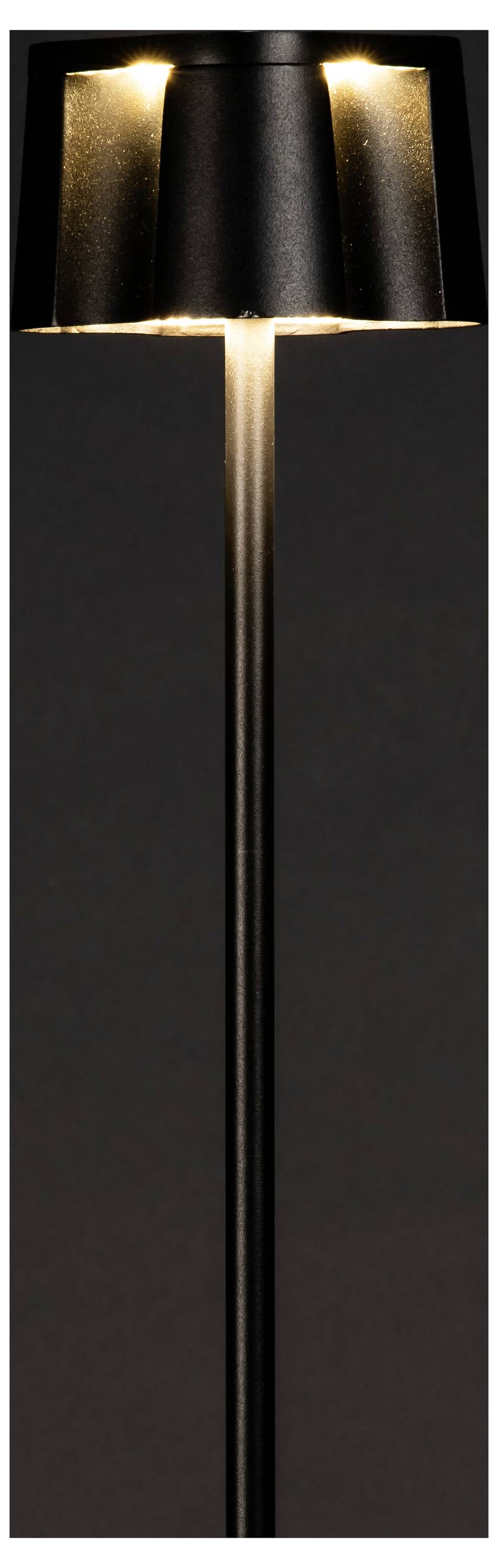 En elegant sort gulvlampe med et moderne design har en kegleformet skærm, der blidt oplyser et dæmpet belyst rum.