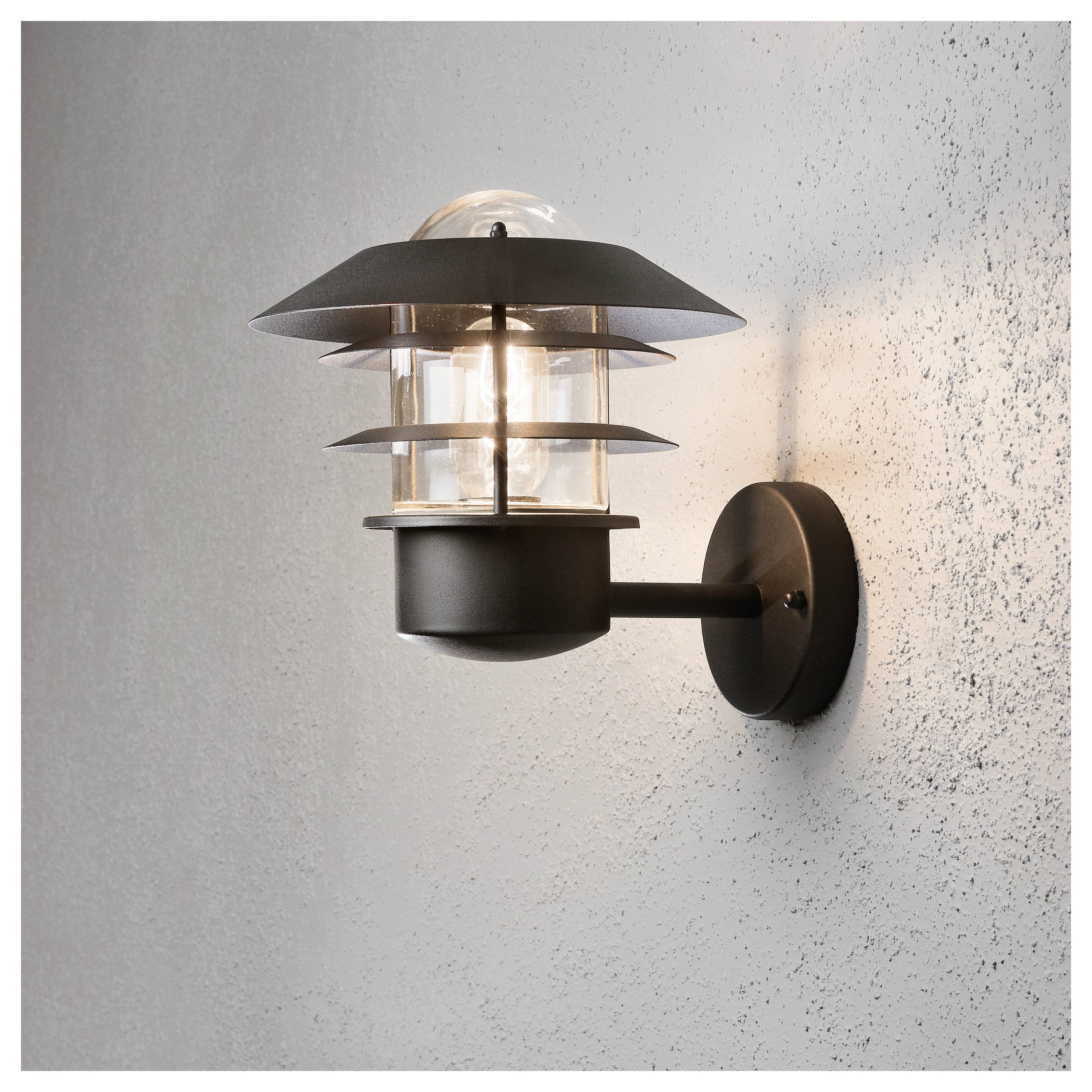 En moderne vægmonteret udendørslampe med en lagdelt metallisk skærm belyser en struktureret grå overflade og skaber en varm, indbydende atmosfære.
