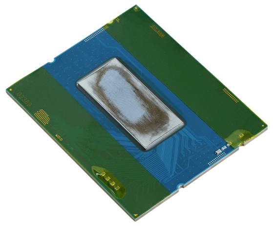 En computerprocesoor eller CPU-chip med en blotlagt die i midten, placeret på et blåt og grønt kredsløbskort.