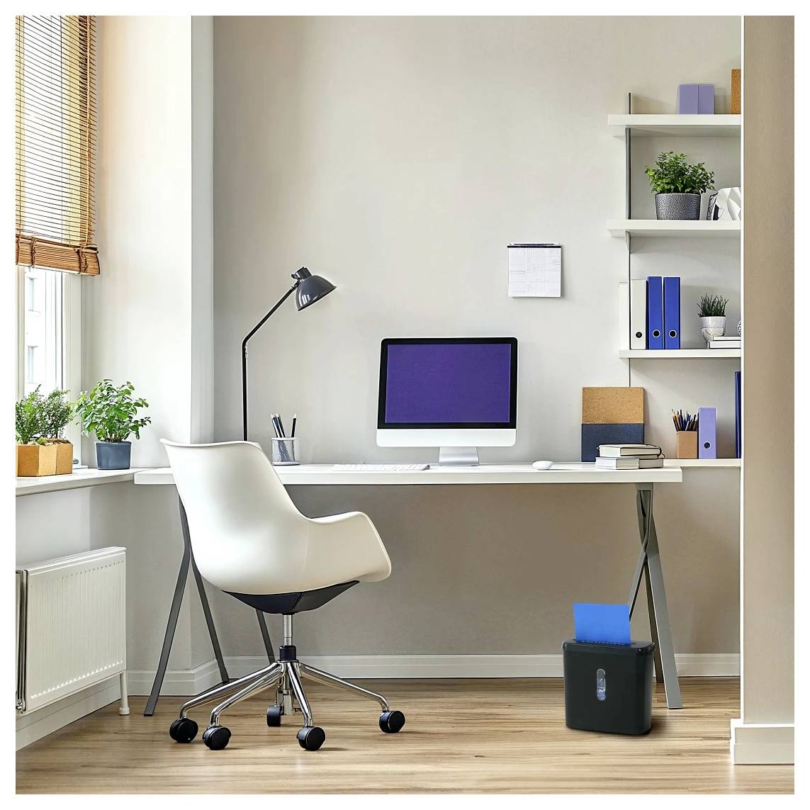Et moderne hjemmekontor med et skrivebord, computer, lampe, stol, hylder med planter og bøger og en papmakuleringsmaskine på gulvet. Lyset fylder rummet.