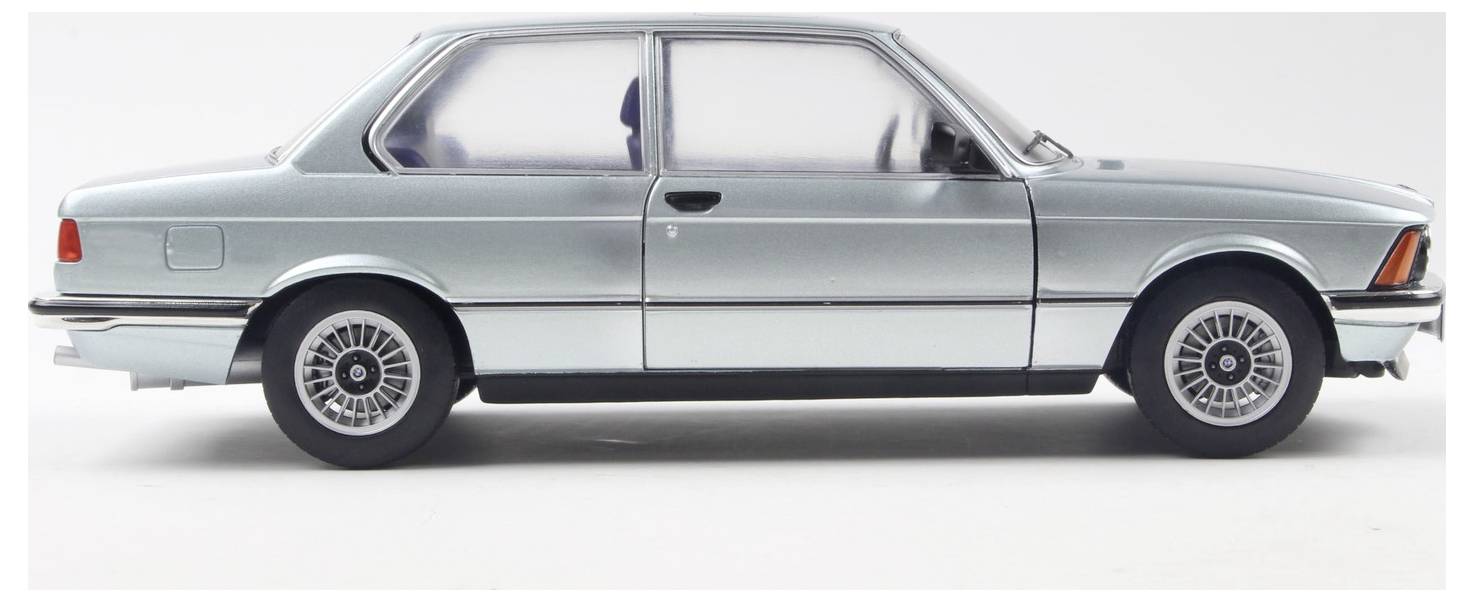 Sidevisning af en vintage sølvfarvet sedan med strømlinet design, sandsynligvis fra slutningen af det 20. århundrede, med karakteristiske aluminiumsfælge.