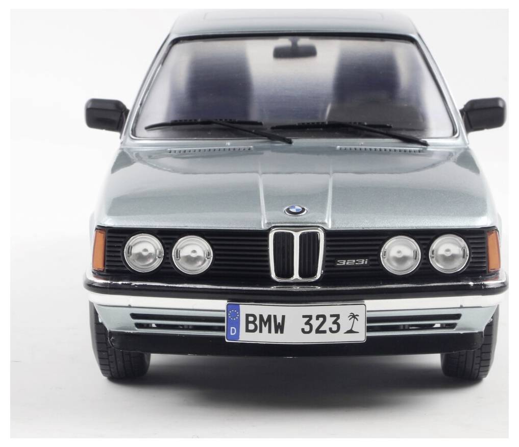 En sølvfarvet vintage BMW sedan vises fra forsiden, hvor bilens grill og forlygter er synlige. Nummerplade læser 'BMW 323'.