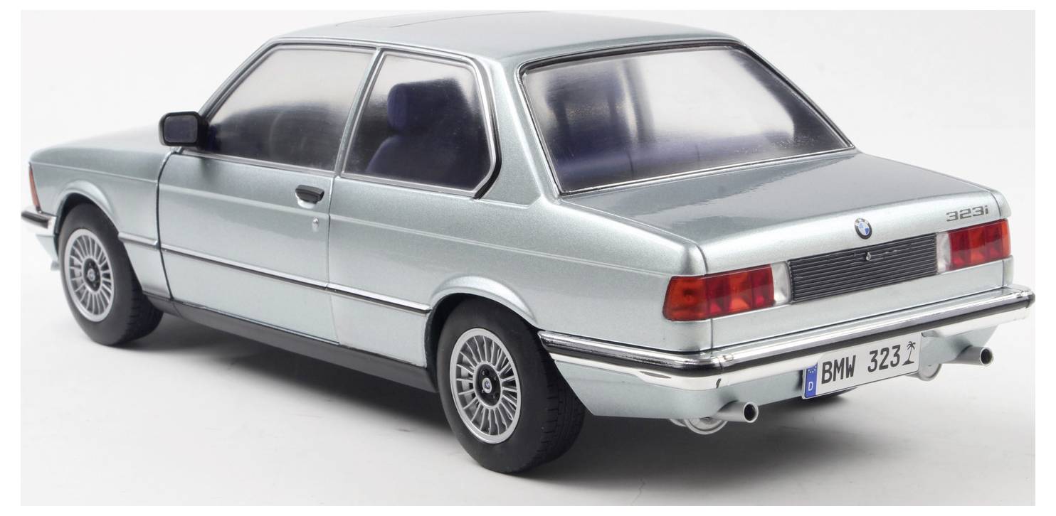 En skaleret model af en vintage BMW 323i bil i metallisk sølv, set fra en bagudvendt vinkel, der fremviser designet og detaljer som baglygterne.