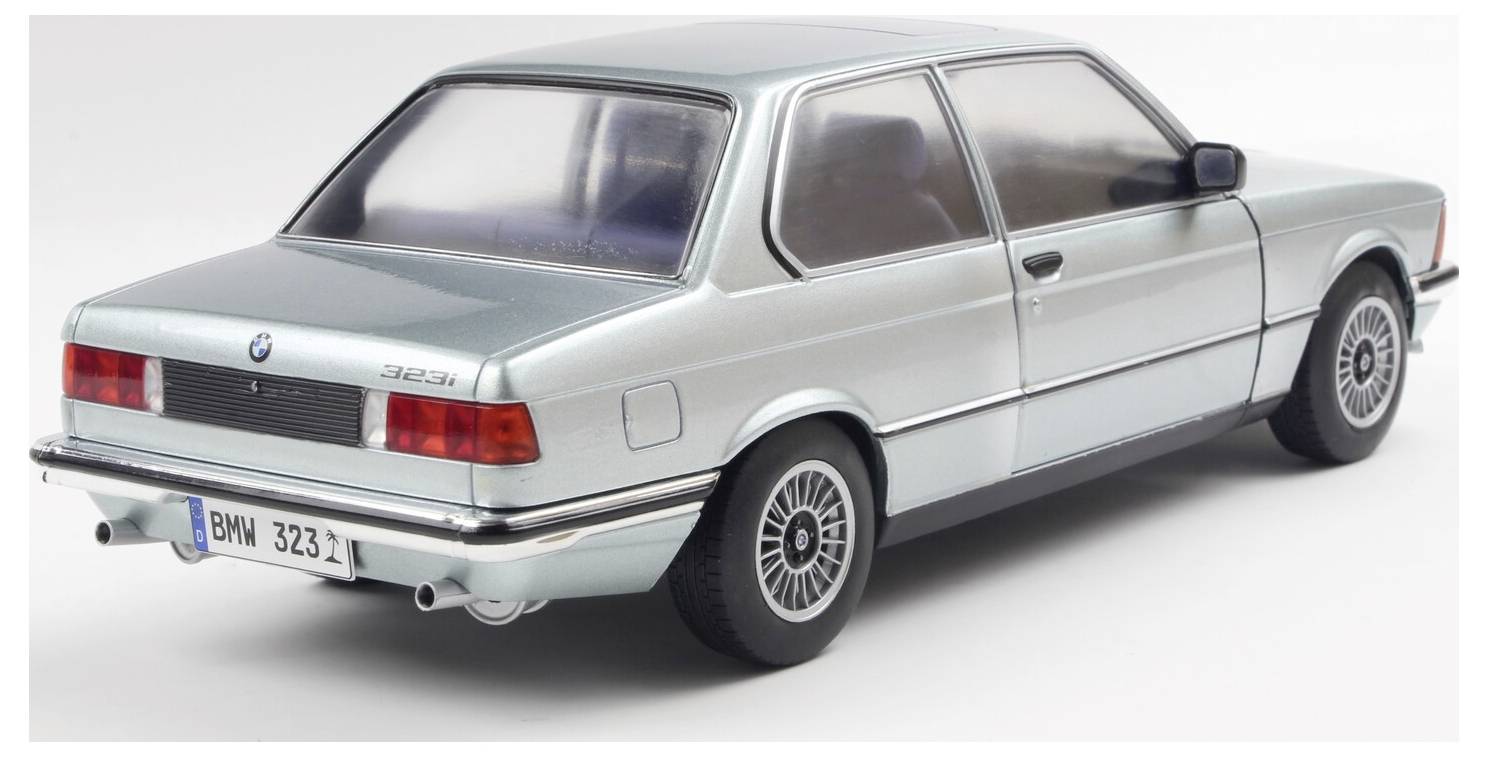 En lyseblå BMW 323i klassisk modelbil, set fra bagvinklen, på en ensfarvet baggrund, der fremhæver dens elegante design og vintage stil.