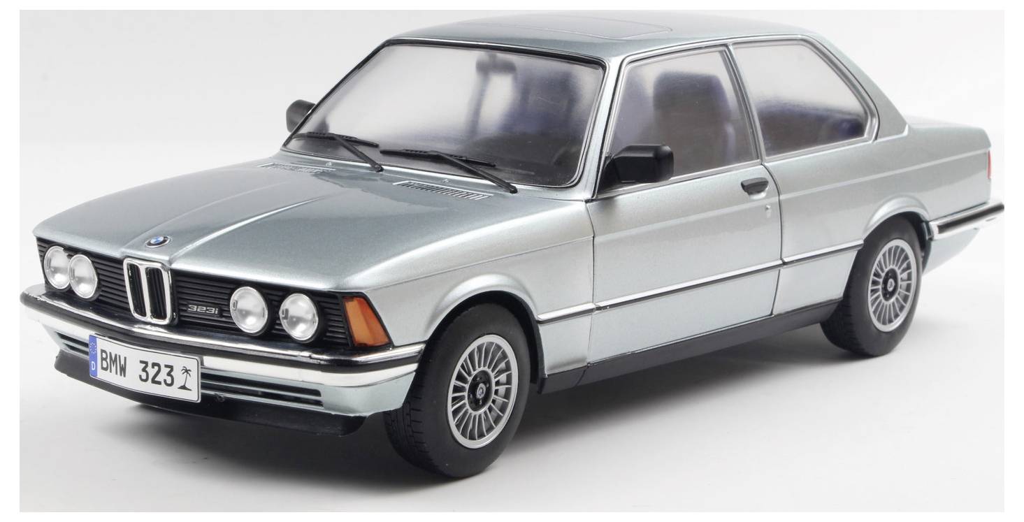 En sølvfarvet BMW 323i sedan fra 1980'erne med to døre, set fra en forfra-vinkel, der viser dens klassiske design og distincte nyre-gitter på en hvid baggrund.