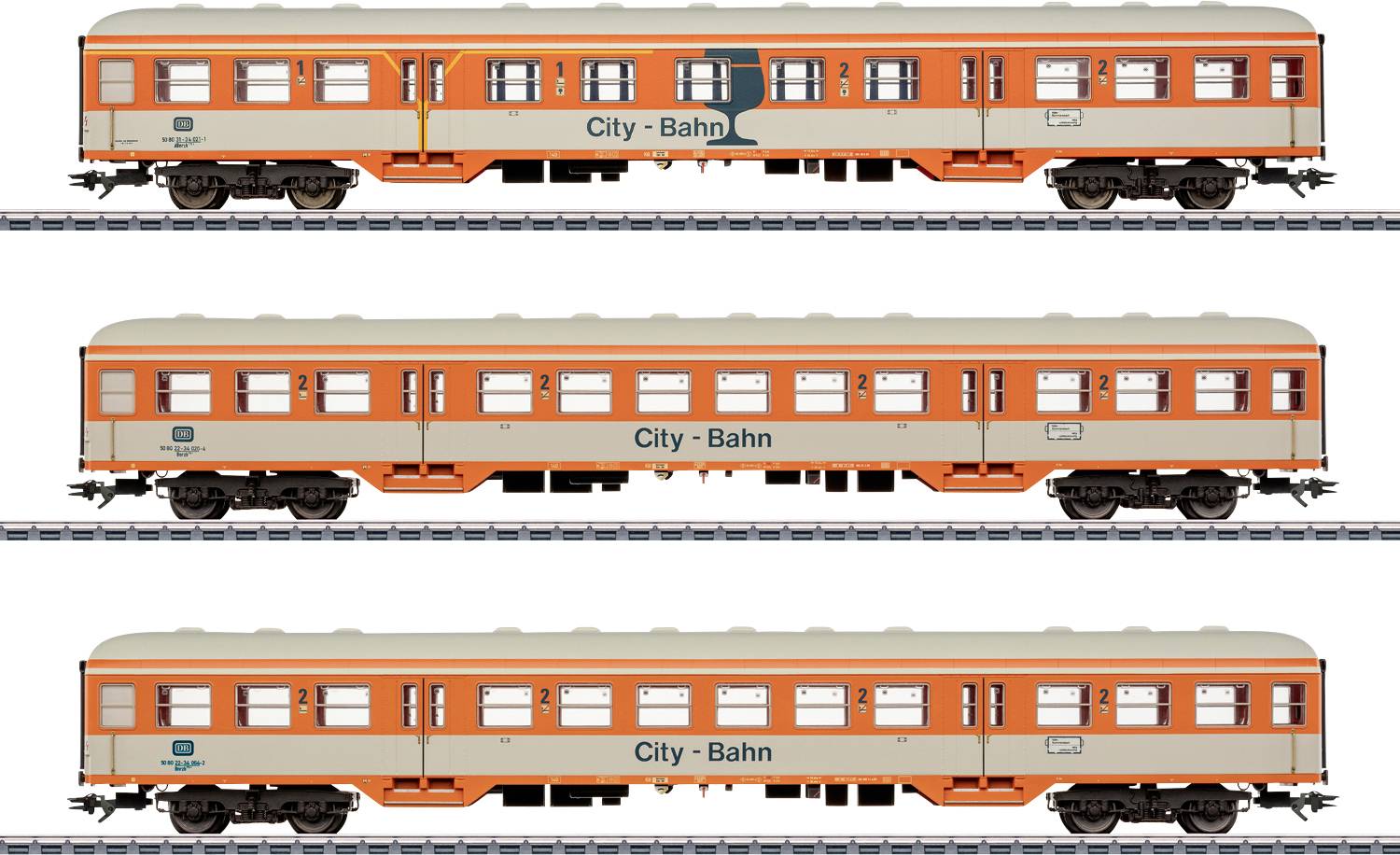 Tre orange og creme City-Bahn togtog på skinner, mærket 'City - Bahn' med forskellige små logoer, set side om side.
