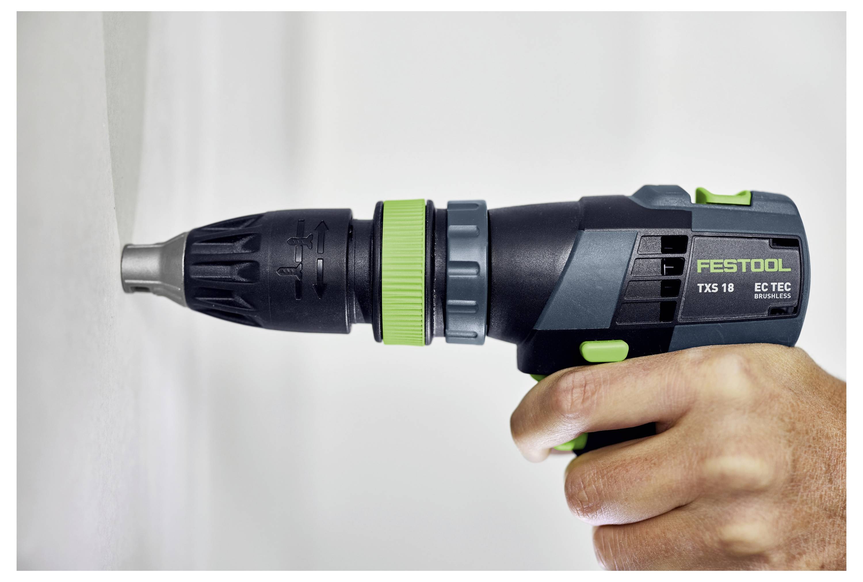 En person bruger en Festool TXS 18 batteridrevet boremaskine til at skrue ind i en hvid overflade og demonstrerer dens funktion i en hjemmeforbedringssammenhæng.