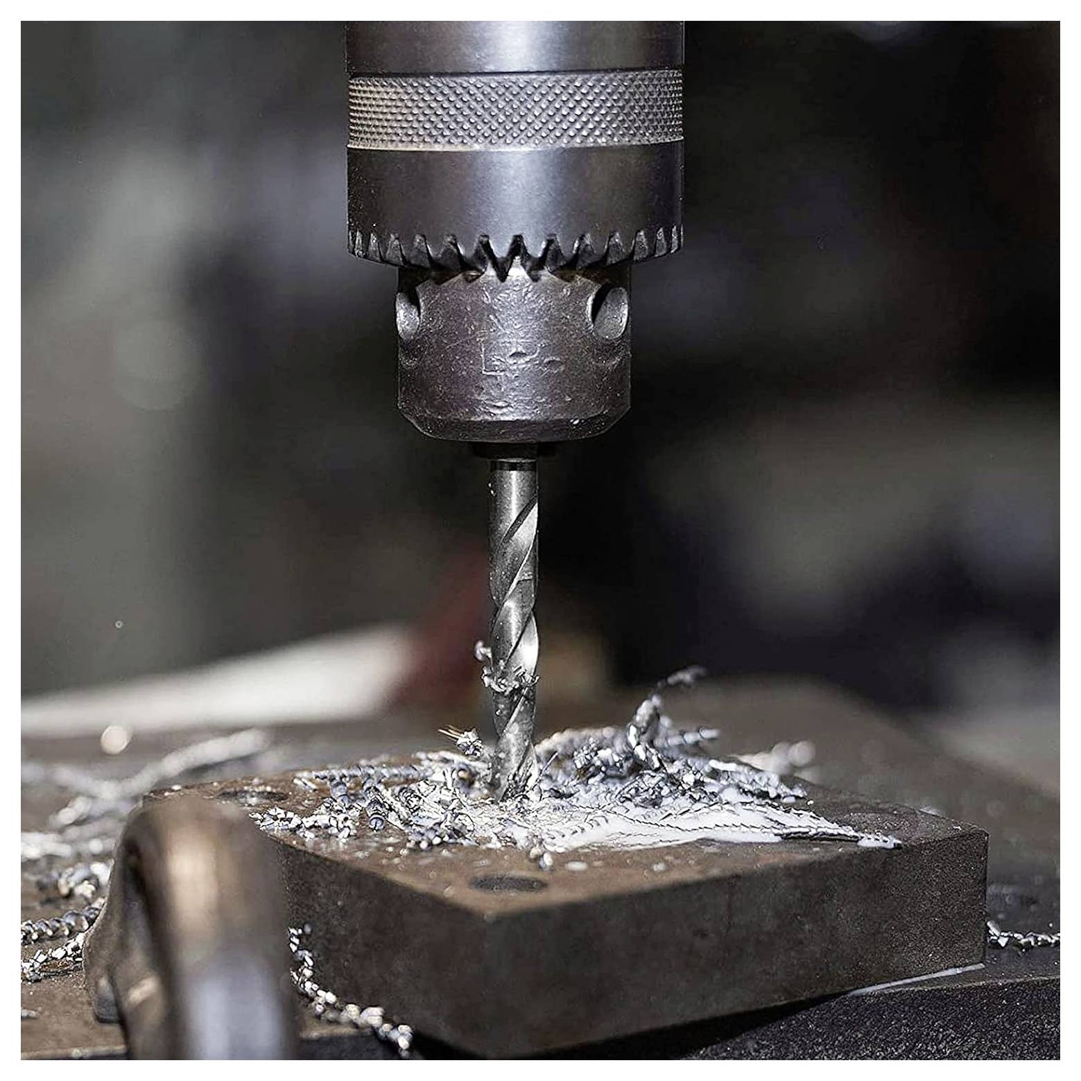 En metaldrilmaskine i drift med en drilbor, der penetrerer en metalblok, omgivet af metalspåner på overfladen.