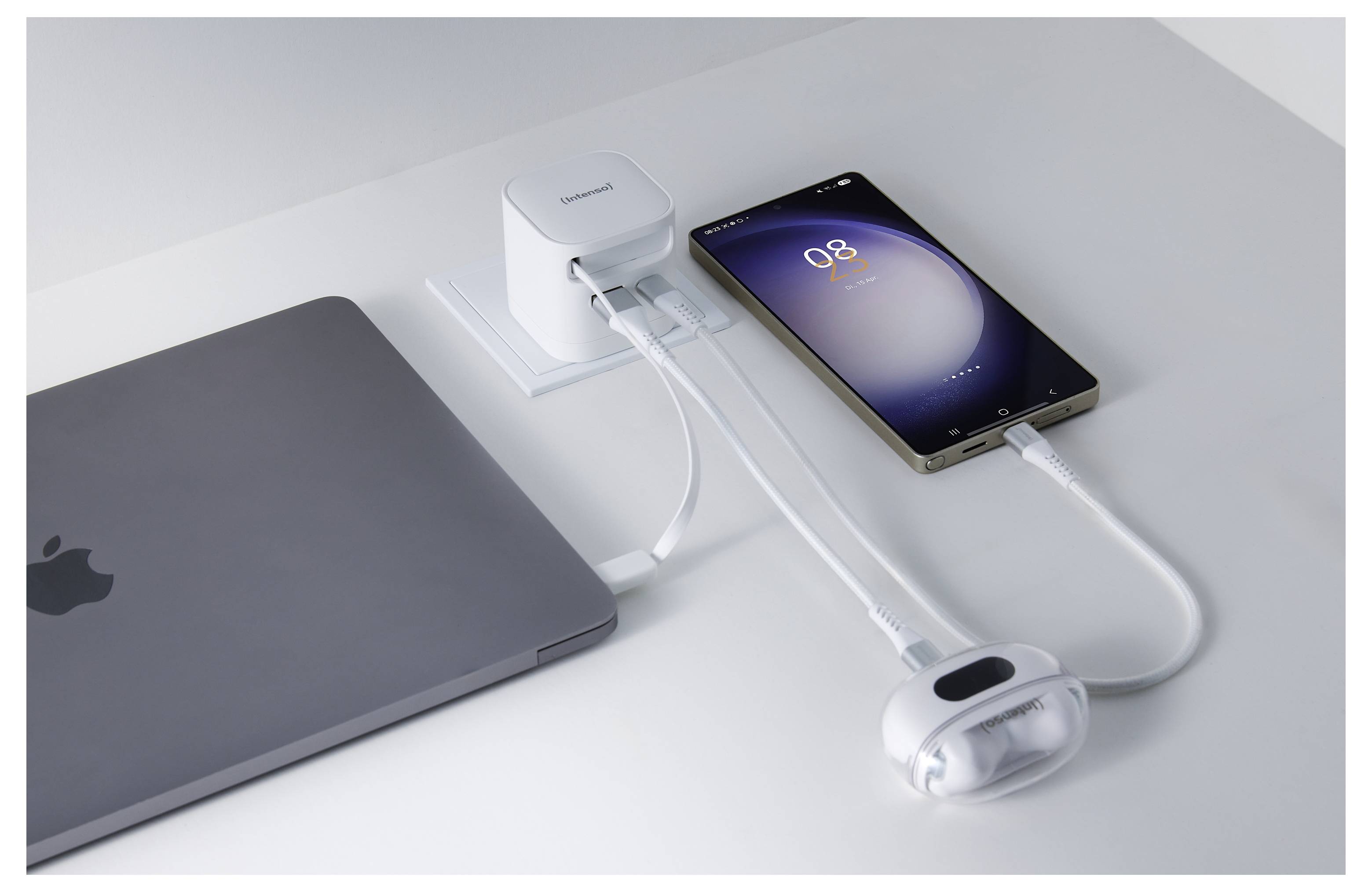 En smartphone, mus og bærbar computer er forbundet til en oplader med flere USB-porte på et hvidt skrivebord, hvilket indikerer enhedsoprencing.