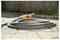 En kvinde og et barn vander planter i en have med en slange. Rosa blomster og træer omgiver dem og skaber et frodig, grønt miljø.
