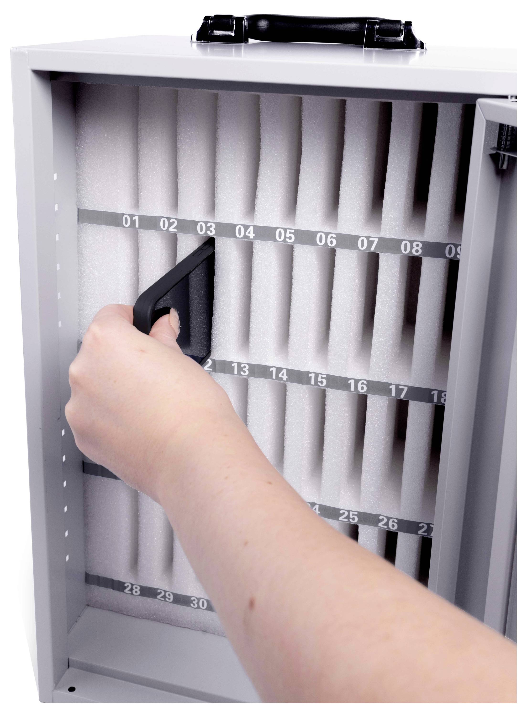 En hånd åbner et korrugeret luftfilter i et vægmonteret HVAC-filterreolhus, der viser nummererede slots på filterrammen.