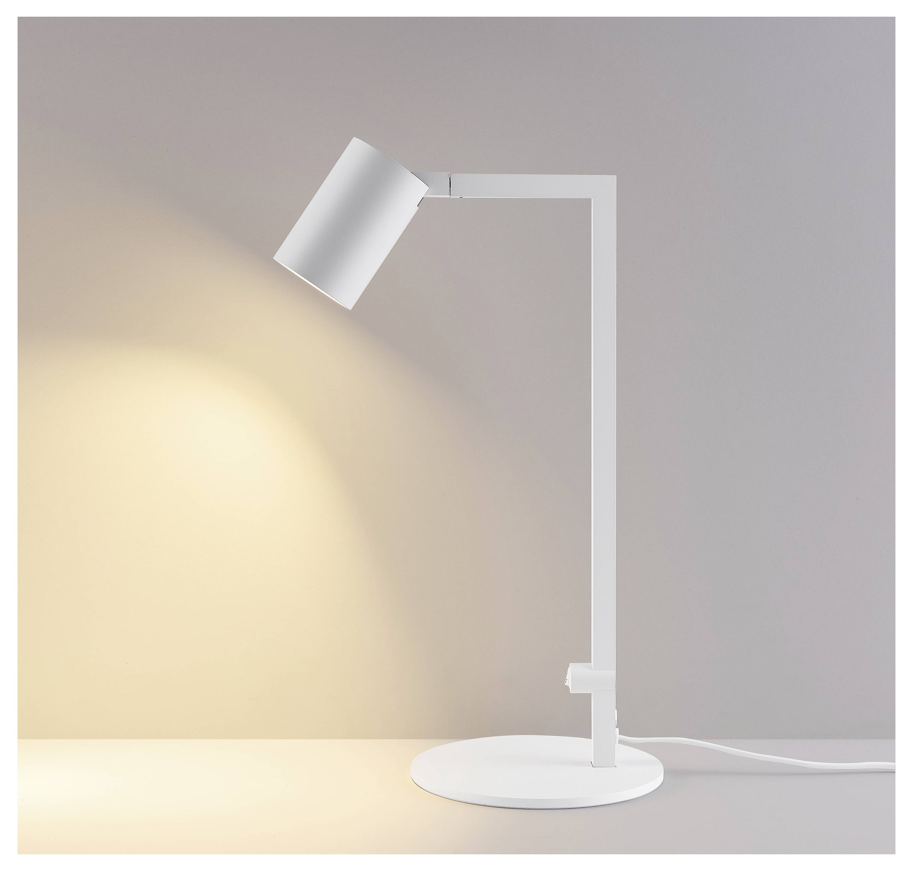 Hvid justerbar skrivebordlampe på en rund sokkel, der kaster et varmt skær mod en plain grå baggrund.