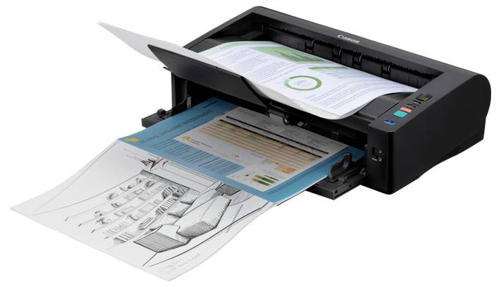 Printer udskriver aktivt flere farvede dokumenter og en sort-hvid tegning, med en side, der bliver ført ud, og en anden, der er indlæst i bakken.